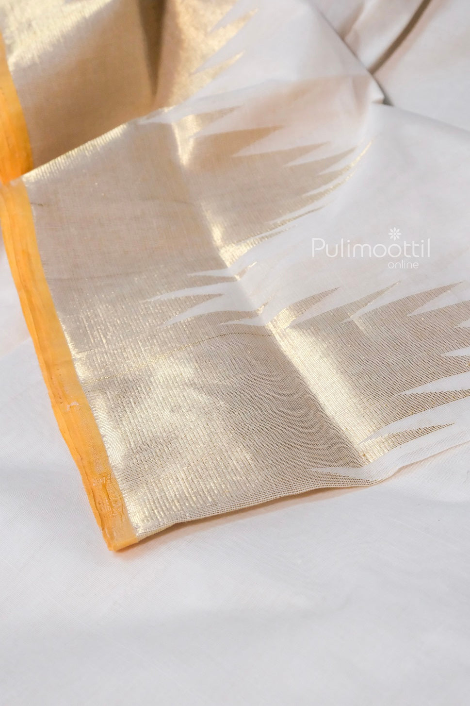 Folded Kerala tissue saree showcasing wide golden stripes on white handloom fabric