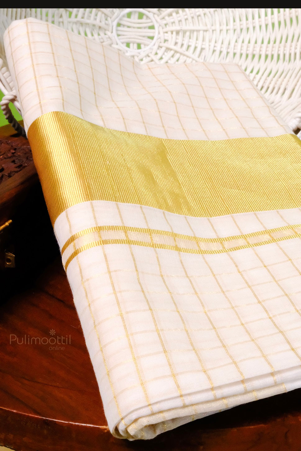 Traditional Kerala kasavu mundu with golden border and checkered design, neatly folded on a wooden surface