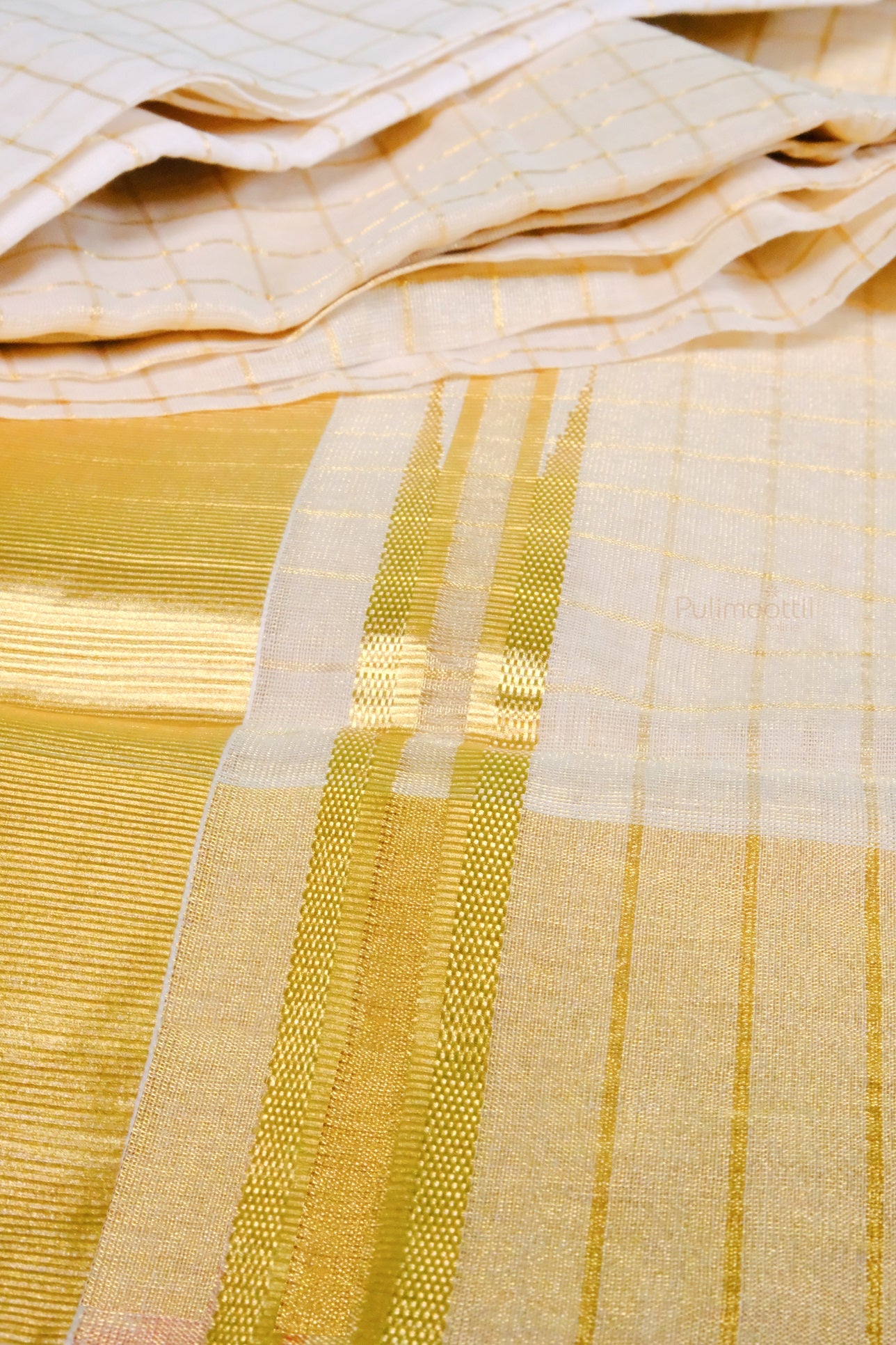 Unfolded Kerala kasavu mundu with golden stripe and fine checked pattern, laid out for detailed view