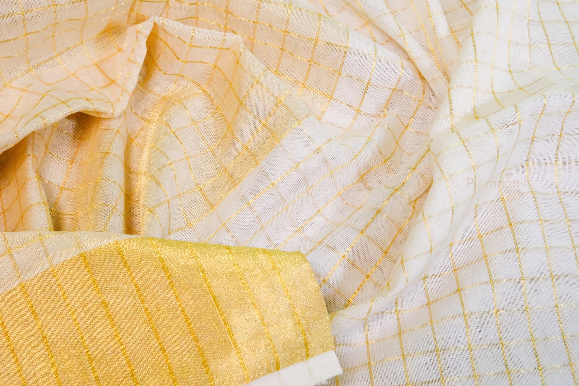 Soft, flowing Kerala mundu fabric with shimmering gold checks and border, showing traditional craftsmanship