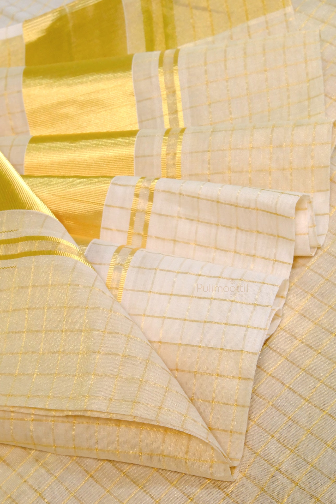 Layered Kerala kasavu mundu with golden zari border and intricate check design, showcasing elegant drape