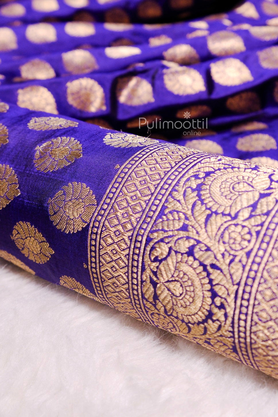 Close-up of gold circular buti patterns and detailed zari border on rich purple Banarasi silk saree with silky sheen.