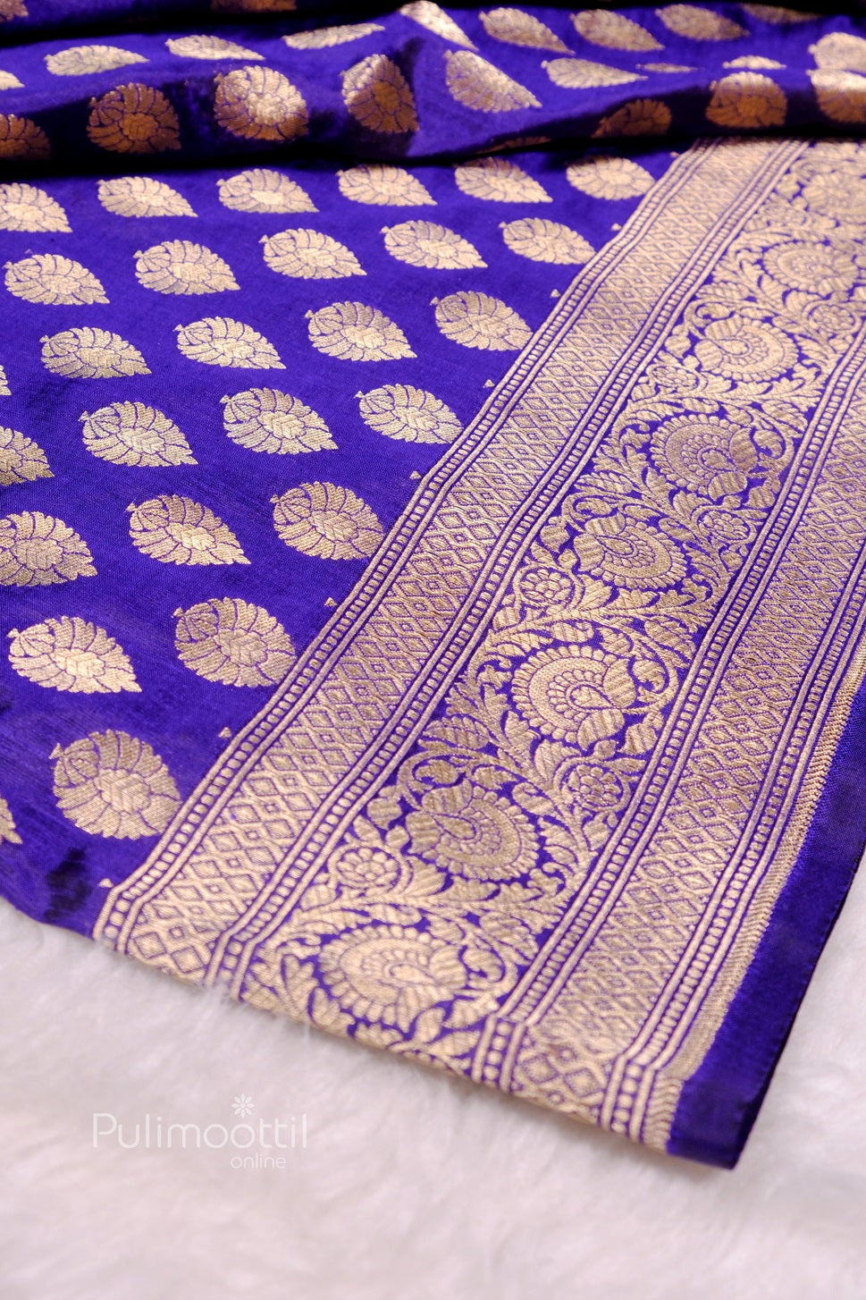 Drape of purple Banarasi silk saree highlighting uniform gold buti pattern and intricate zari border.