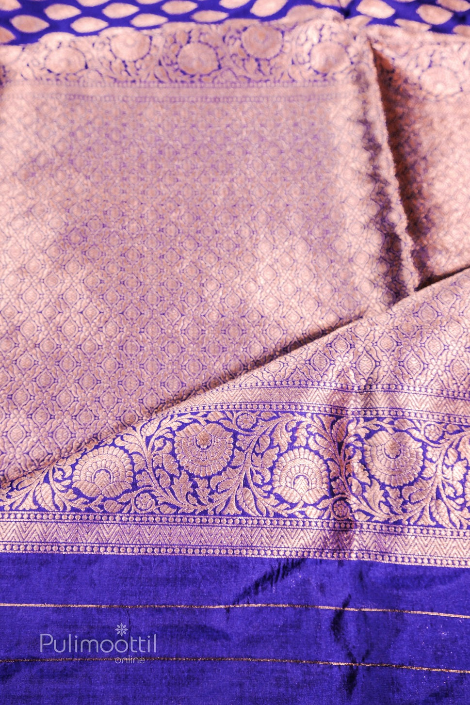 Pallu section of purple Banarasi silk saree with dense golden zari floral motifs, showing sheen and weave detail.