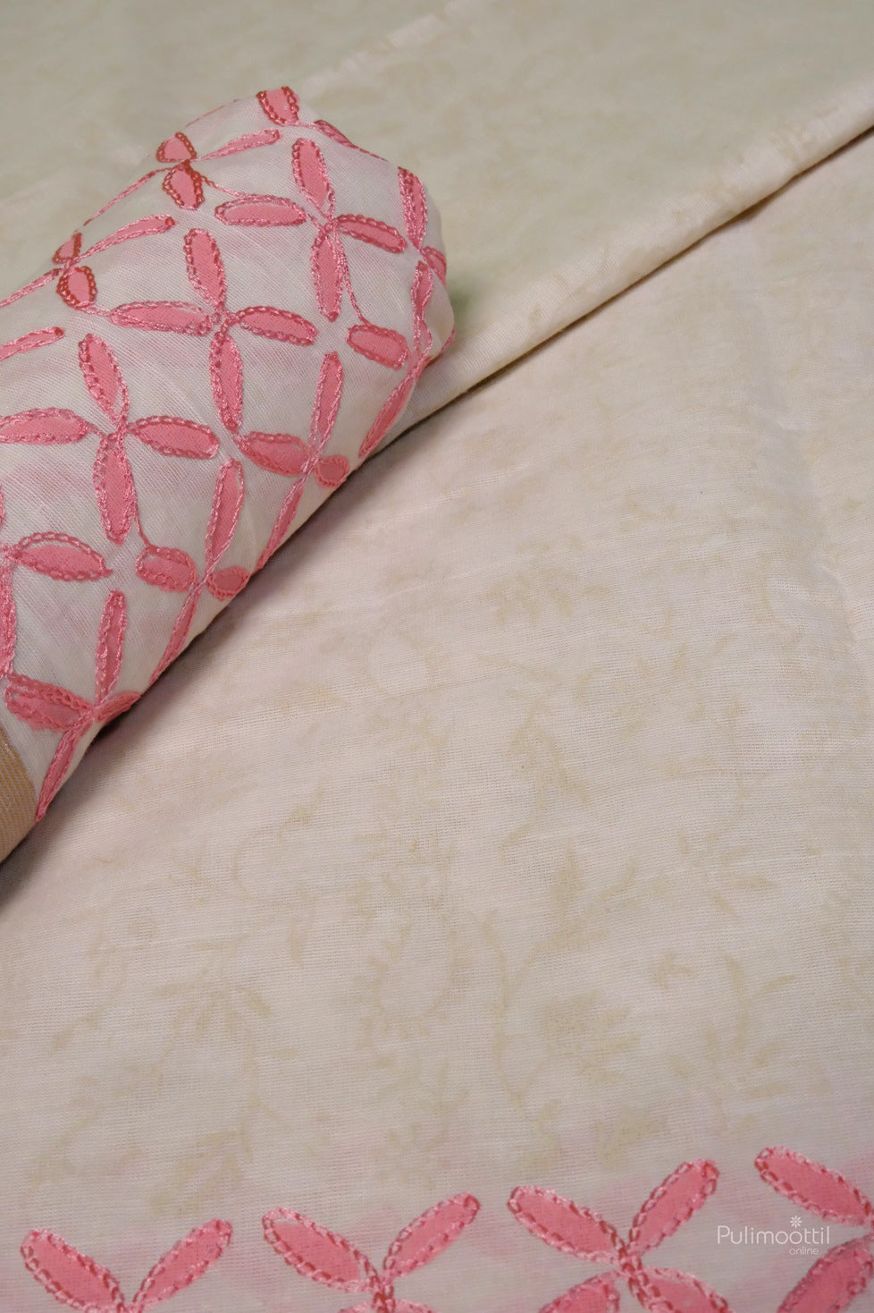 Folded Kerala traditional cotton saree showcasing detailed pink embroidery and subtle floral texture on the body