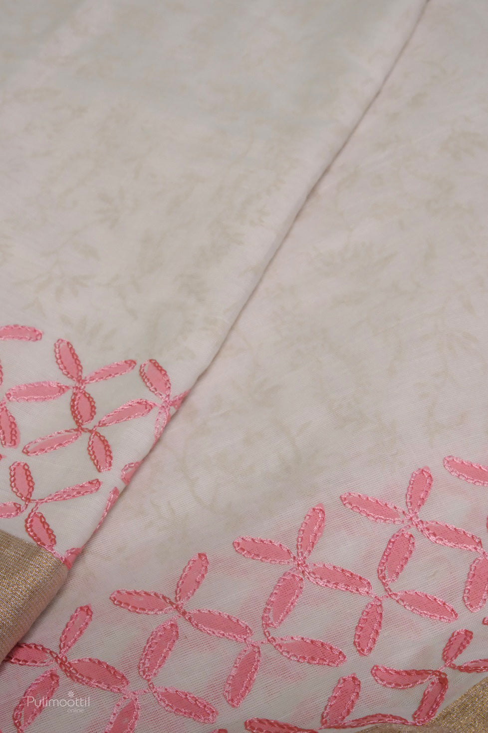 Close-up of Kerala cotton saree with light beige base and pink floral embroidery along the border.