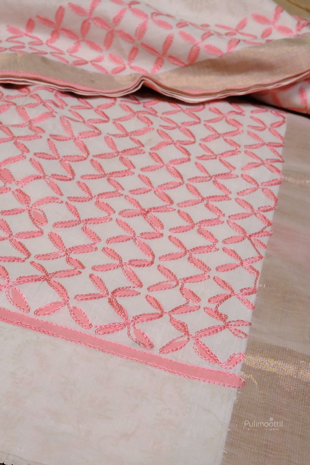 Traditional Kerala cotton saree featuring intricate pink thread embroidery in geometric floral patterns with a subtle beige-gold border.