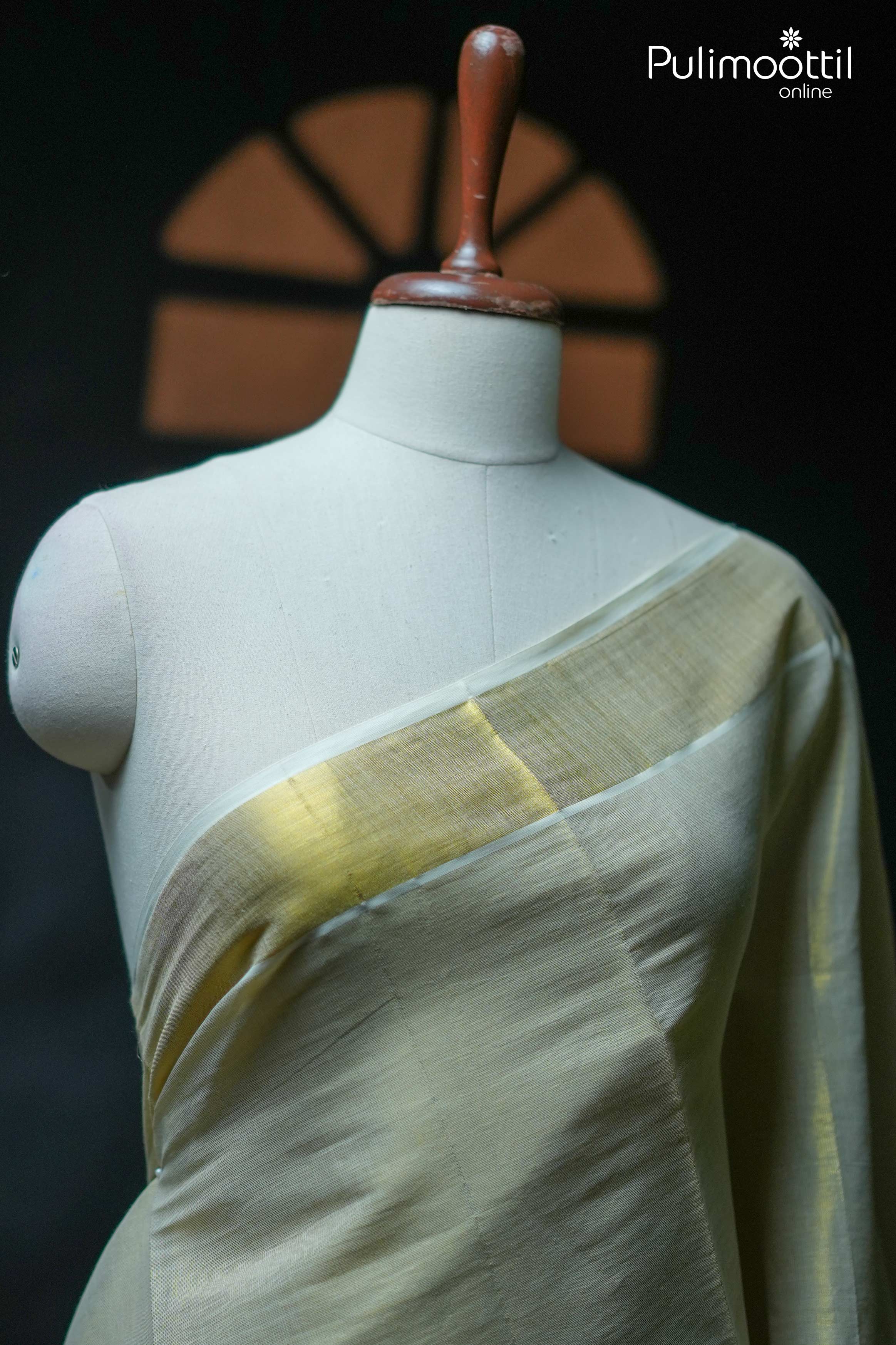 Kerala traditional golden tissue saree with soft off-white body and golden tissue border draped on mannequin.