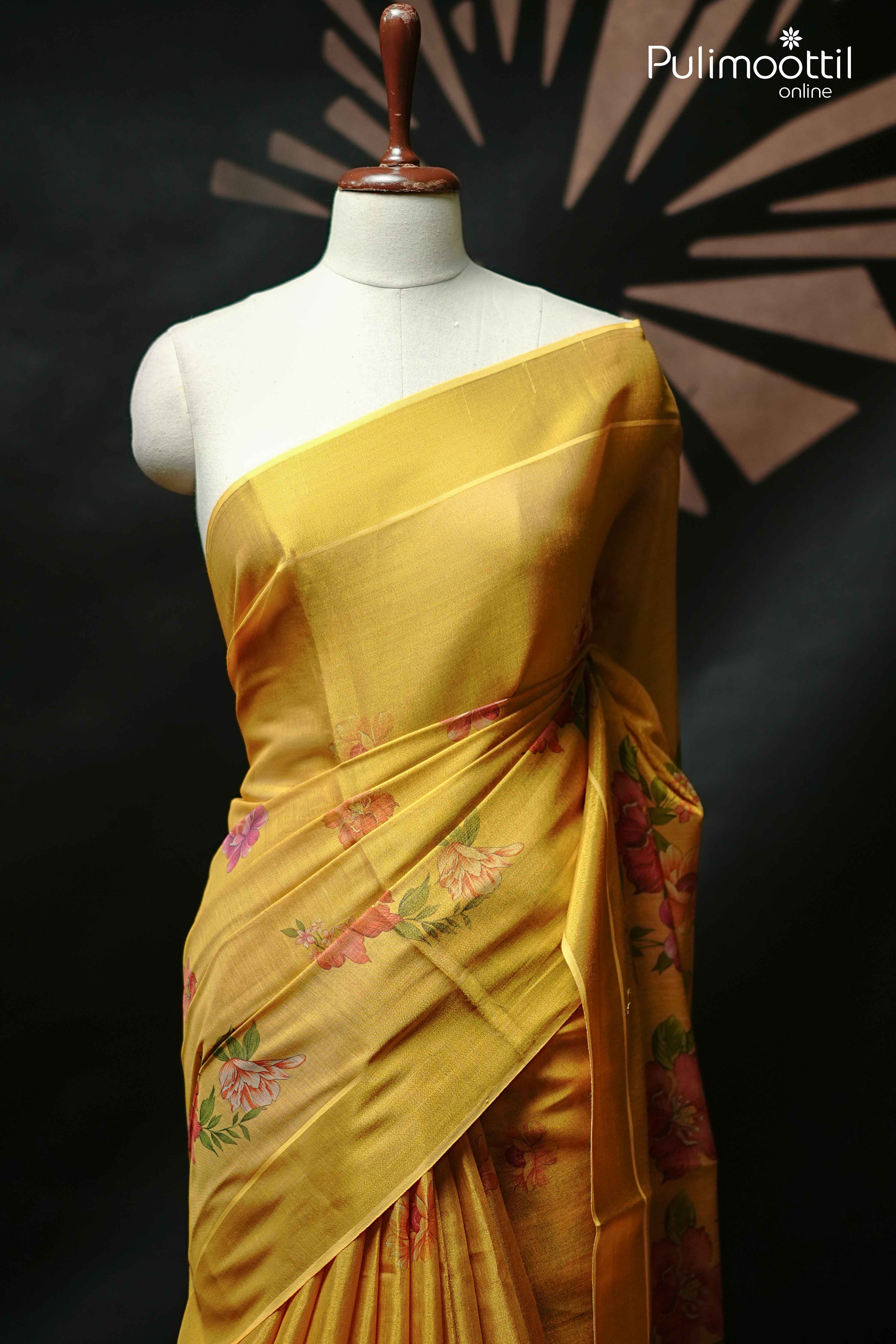 Golden yellow Kerala tissue set saree draped on mannequin, featuring multicolour floral print and a sleek traditional border.