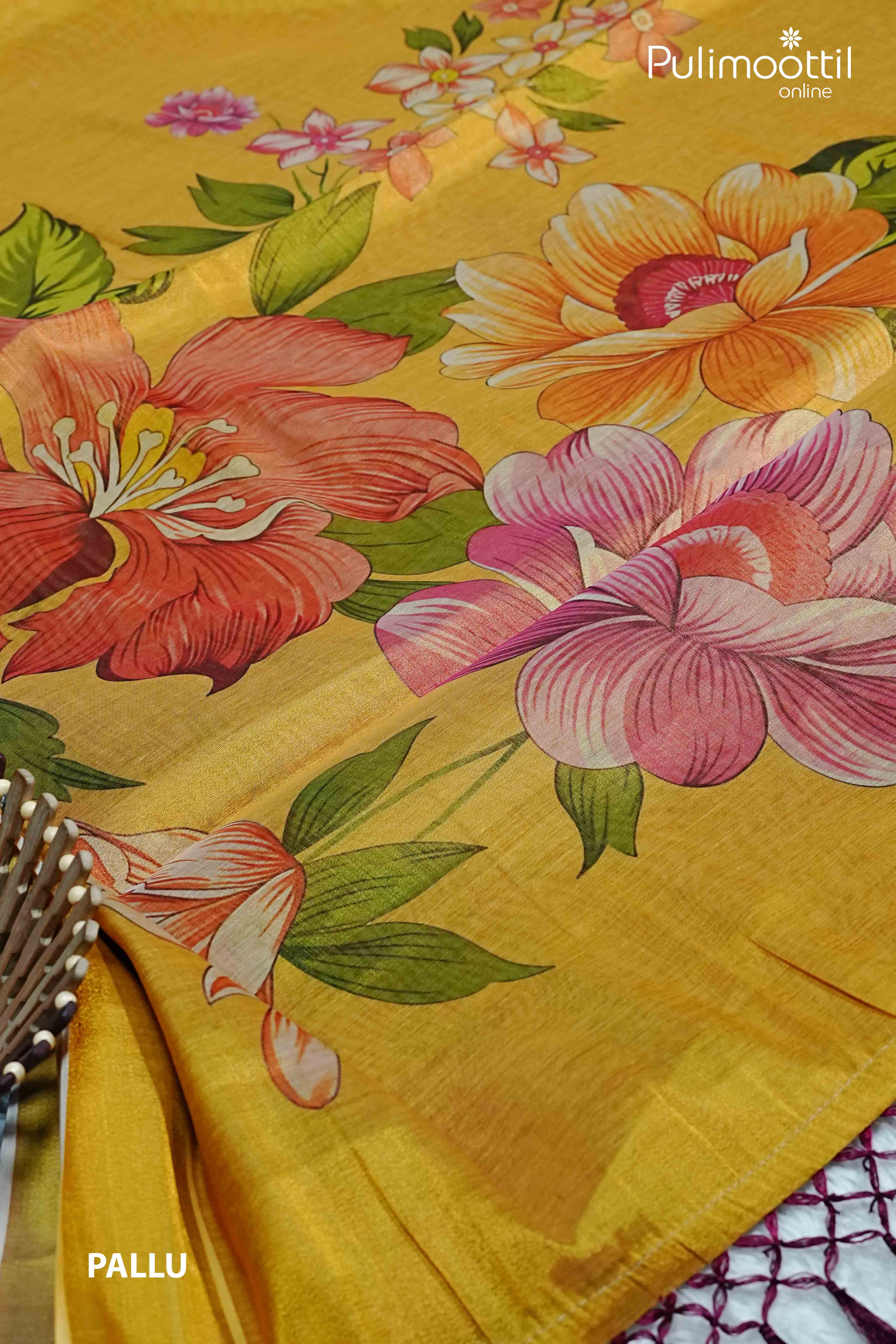 Golden yellow Kerala tissue saree pallu with large multicolour floral prints in orange, pink, and red, laid flat with basket and net detailing.