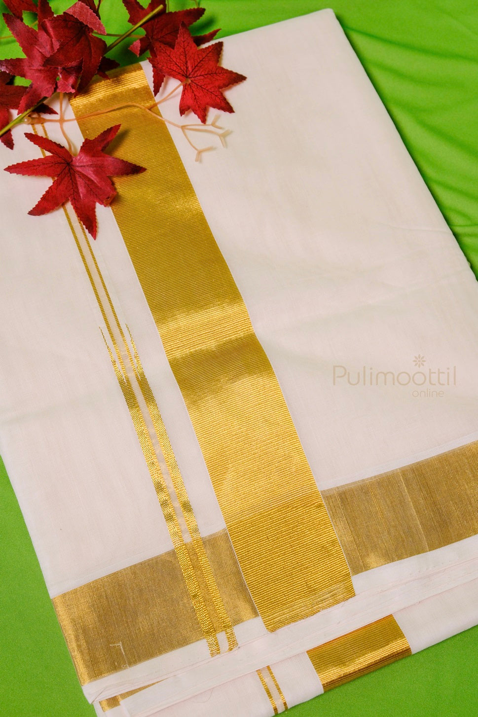Folded Kerala kasavu mundu with gold zari border and red decorative leaves on top