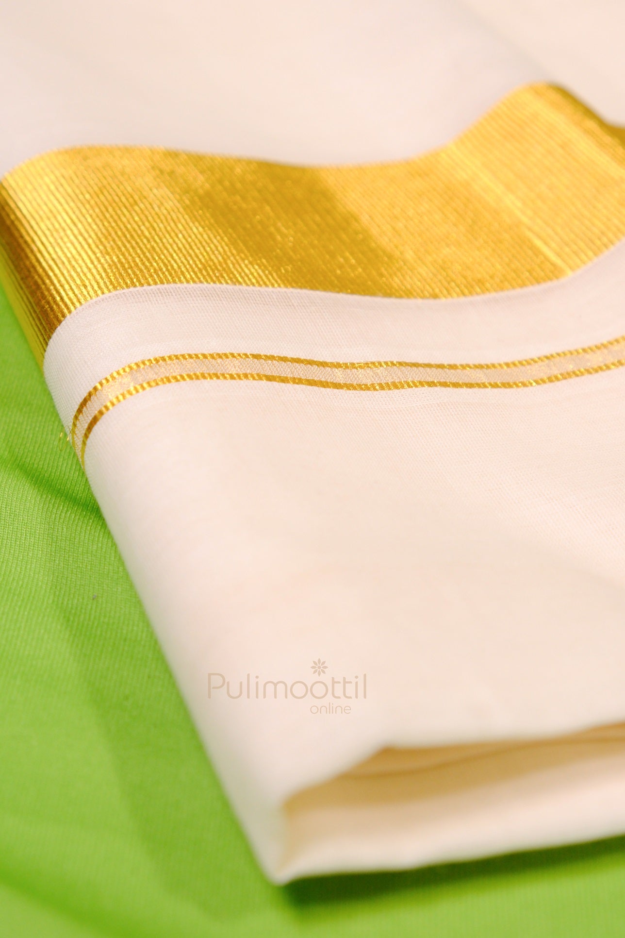 Neatly folded Kerala kasavu mundu with minimal golden border on white cotton fabric