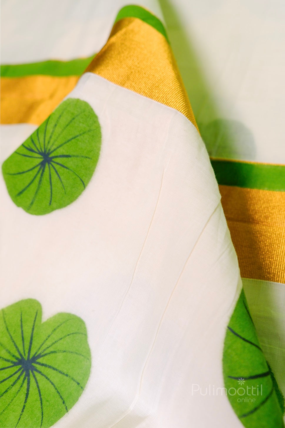 Close-up of golden zari border with green floral print on Kerala tissue saree – elegant handloom look