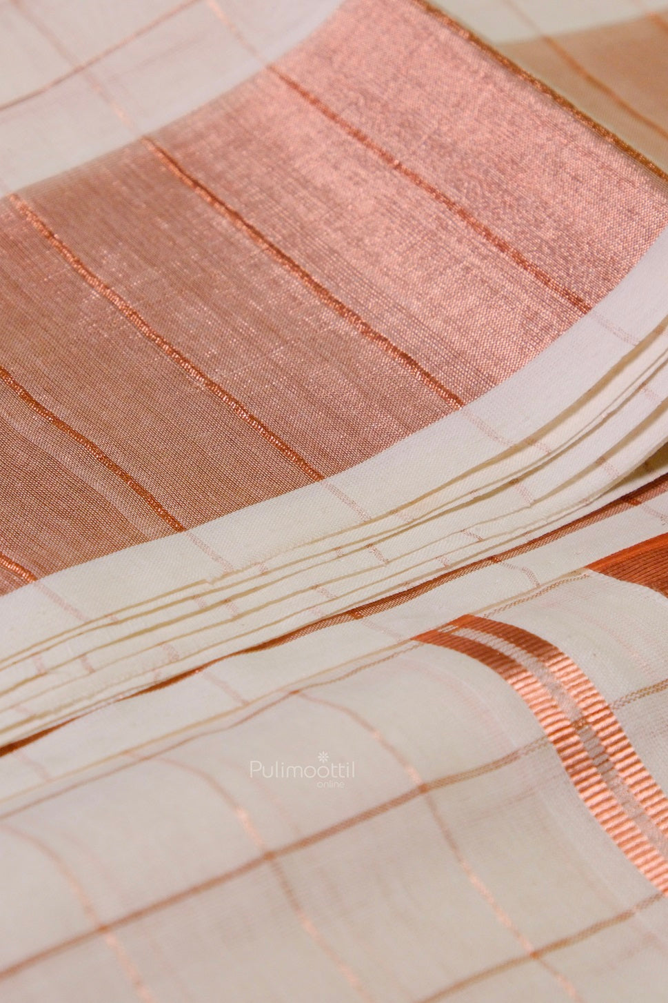 Detailed view of Kerala Kasavu saree highlighting its woven copper pallu and minimalist check pattern on off-white base.