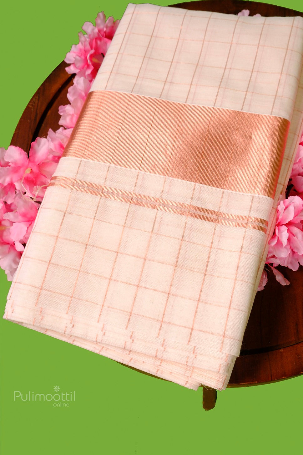 Elegant Kerala Kasavu saree with copper zari border and soft checkered pattern, displayed on a wooden table with pink flowers.