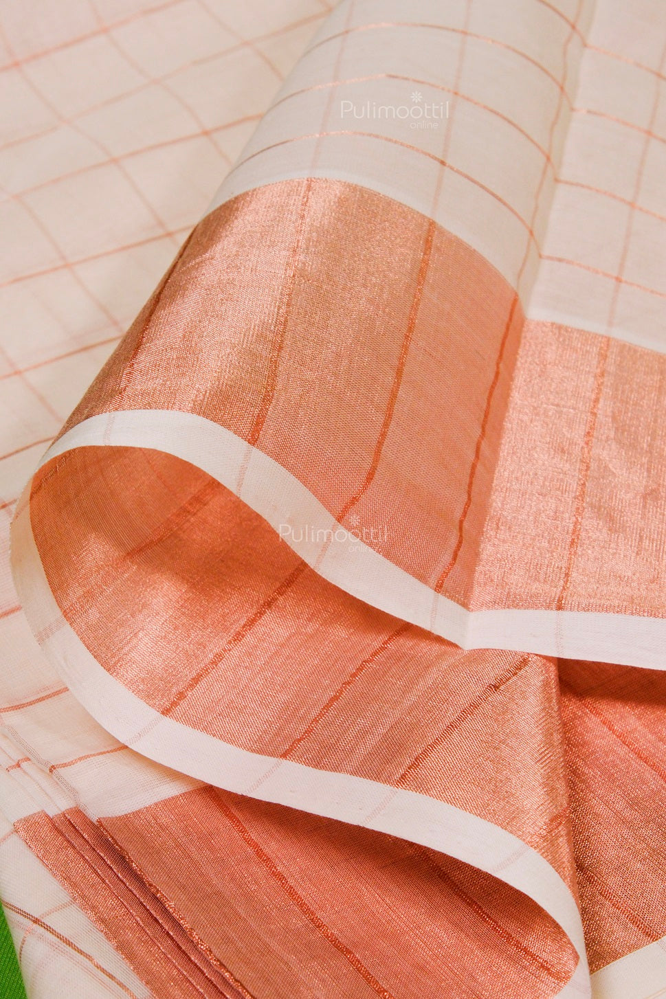 Classic Kasavu saree with shimmering copper zari pallu and soft check weave, artistically draped for texture display.