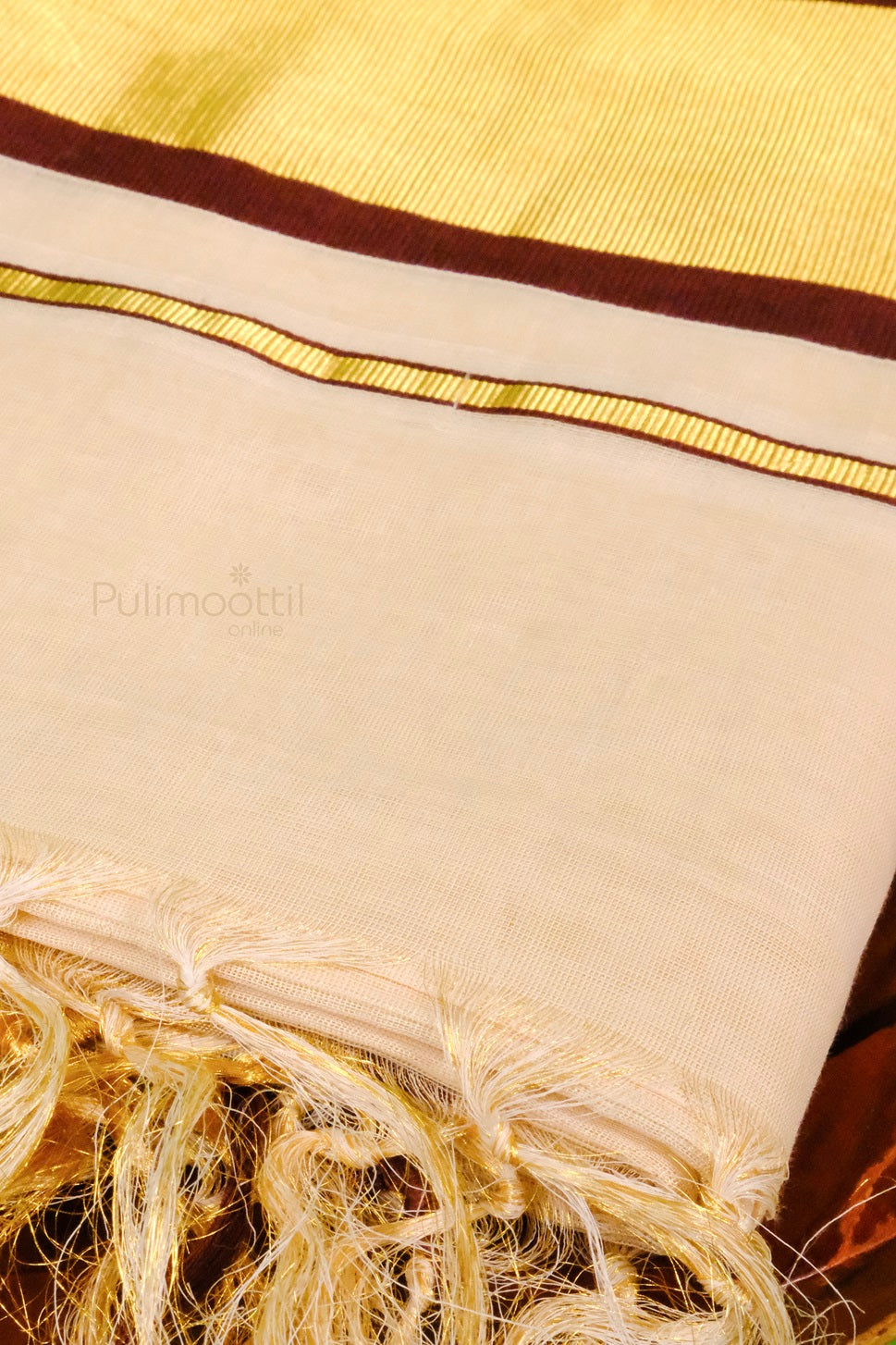 Detailed view of the traditional kasavu mundu’s border featuring triple golden lines and maroon accents with hand-knotted fringes.