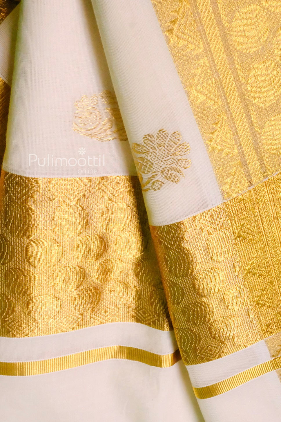 Kerala saree with prominent gold zari border and floral buttas on the body, showcasing the blend of tradition and elegance.