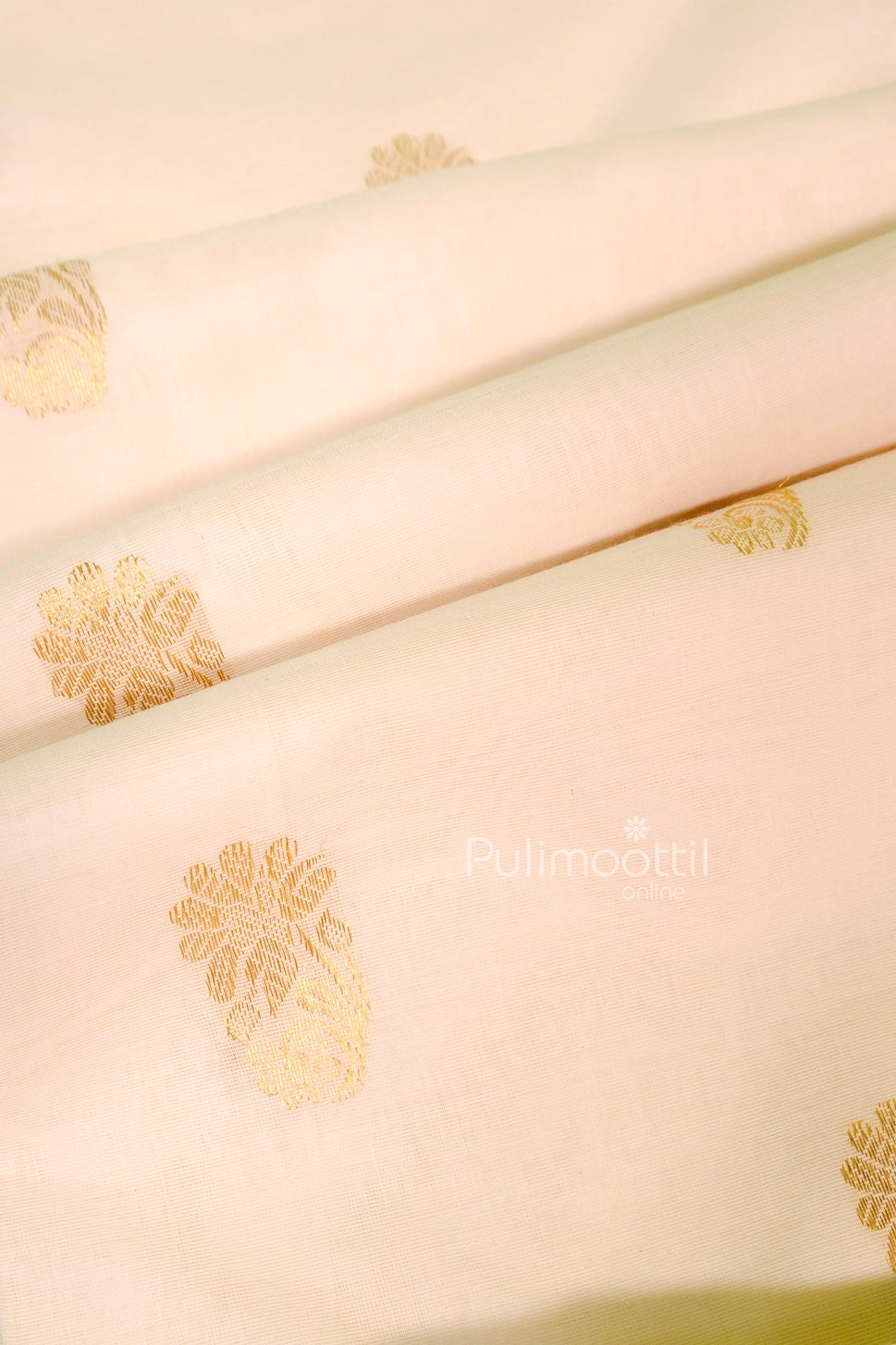 Detailed view of the off-white saree fabric featuring golden floral motifs woven throughout.