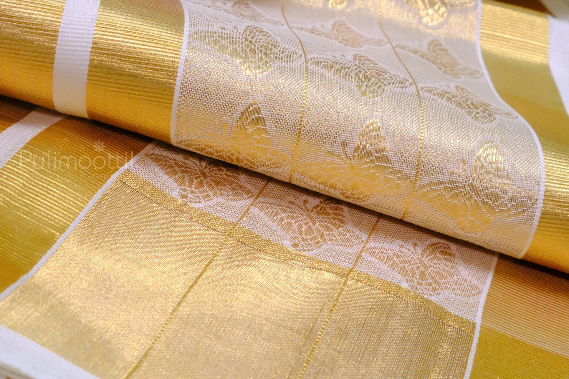 Folded Kerala kasavu mundu with golden zari border and butterfly motifs, neatly placed on a wooden table.