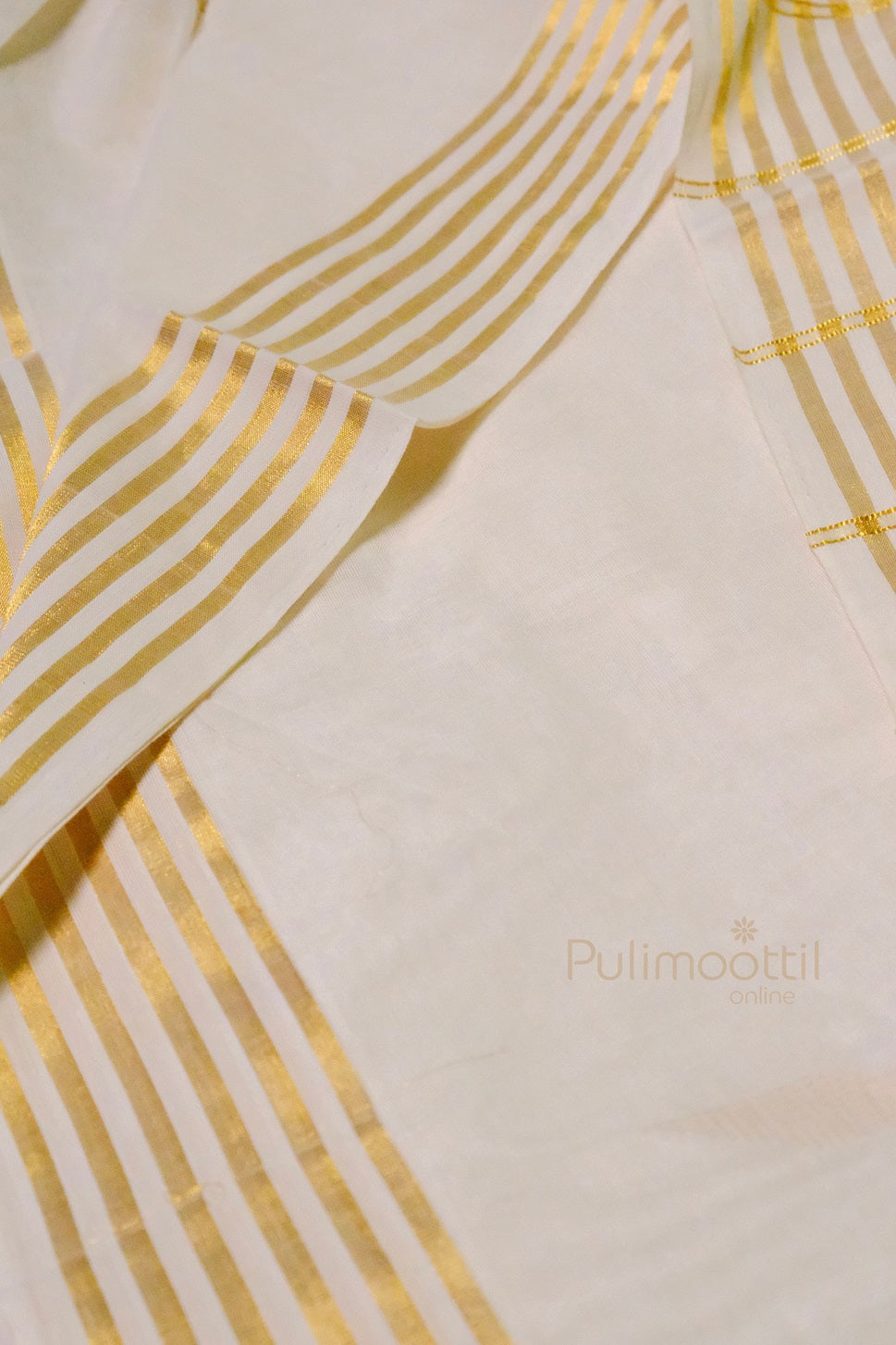 Traditional Kerala kasavu saree laid out to display golden striped pallu and intricate border detailing