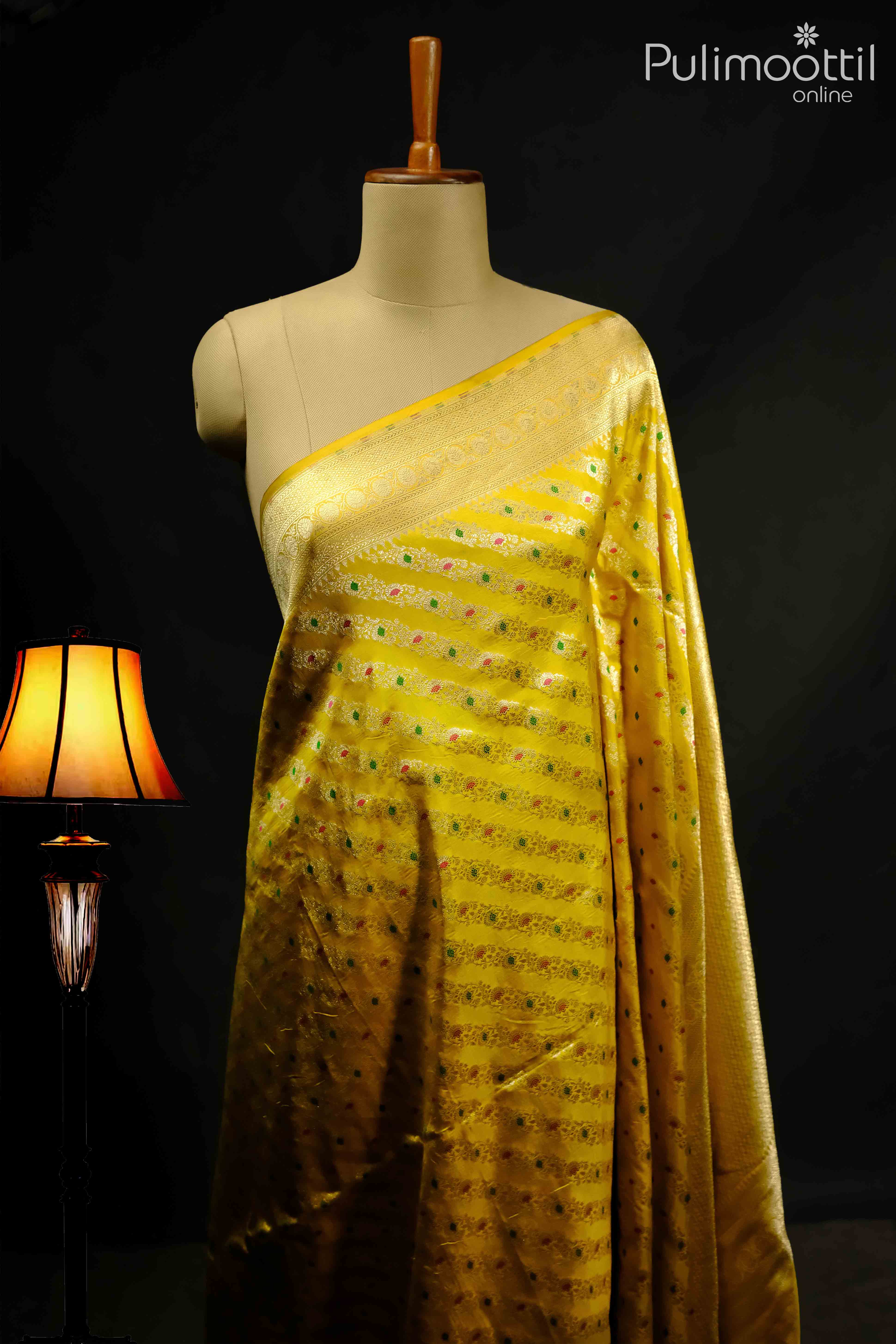 Lemon yellow pure Banarasi silk saree with slanting floral design and golden border, displayed on a mannequin, perfect for weddings and festive occasions.