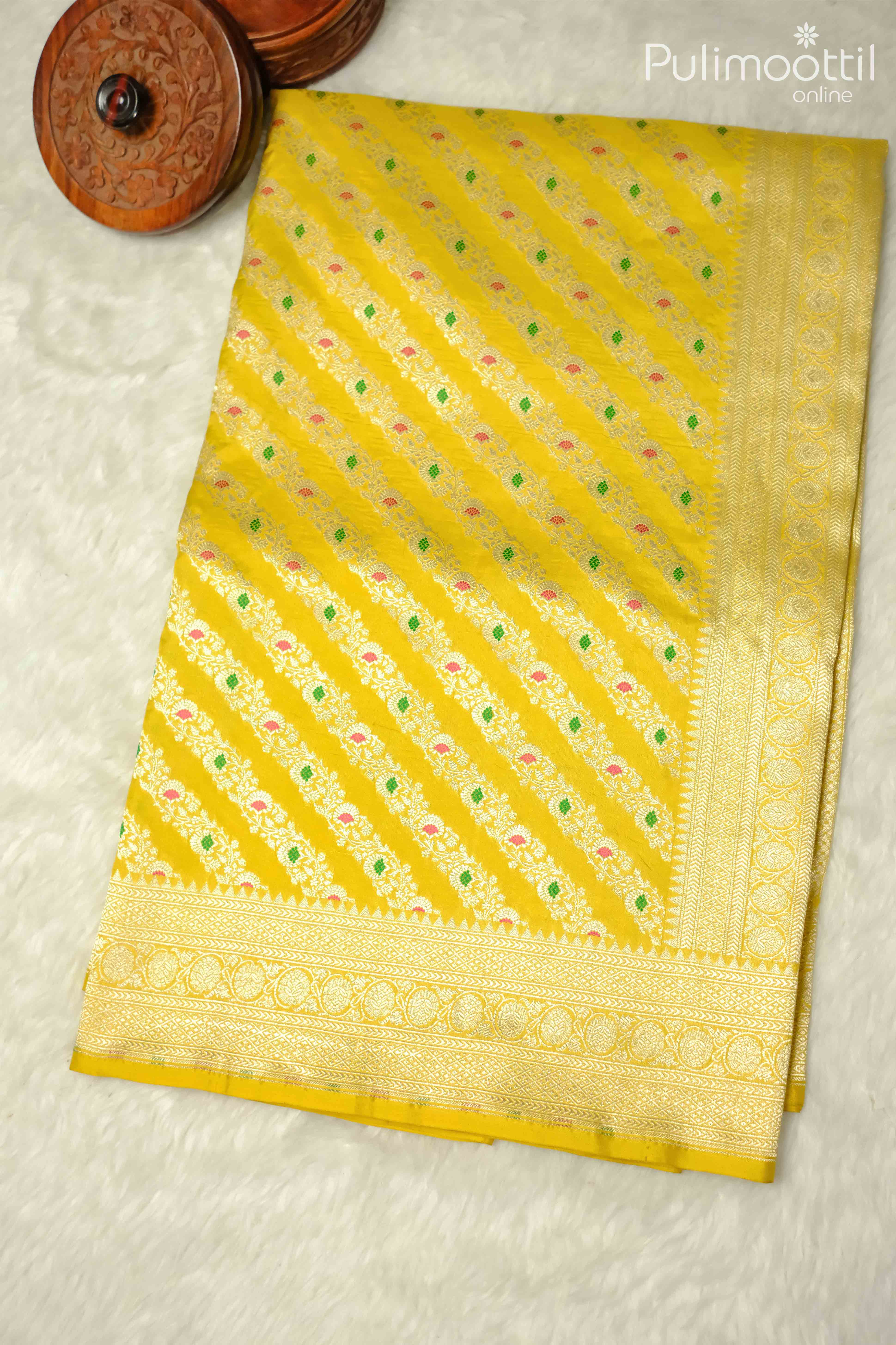 Lemon yellow pure Banarasi silk saree with slanting floral design and golden border, displayed on a mannequin, perfect for weddings and festive occasions.