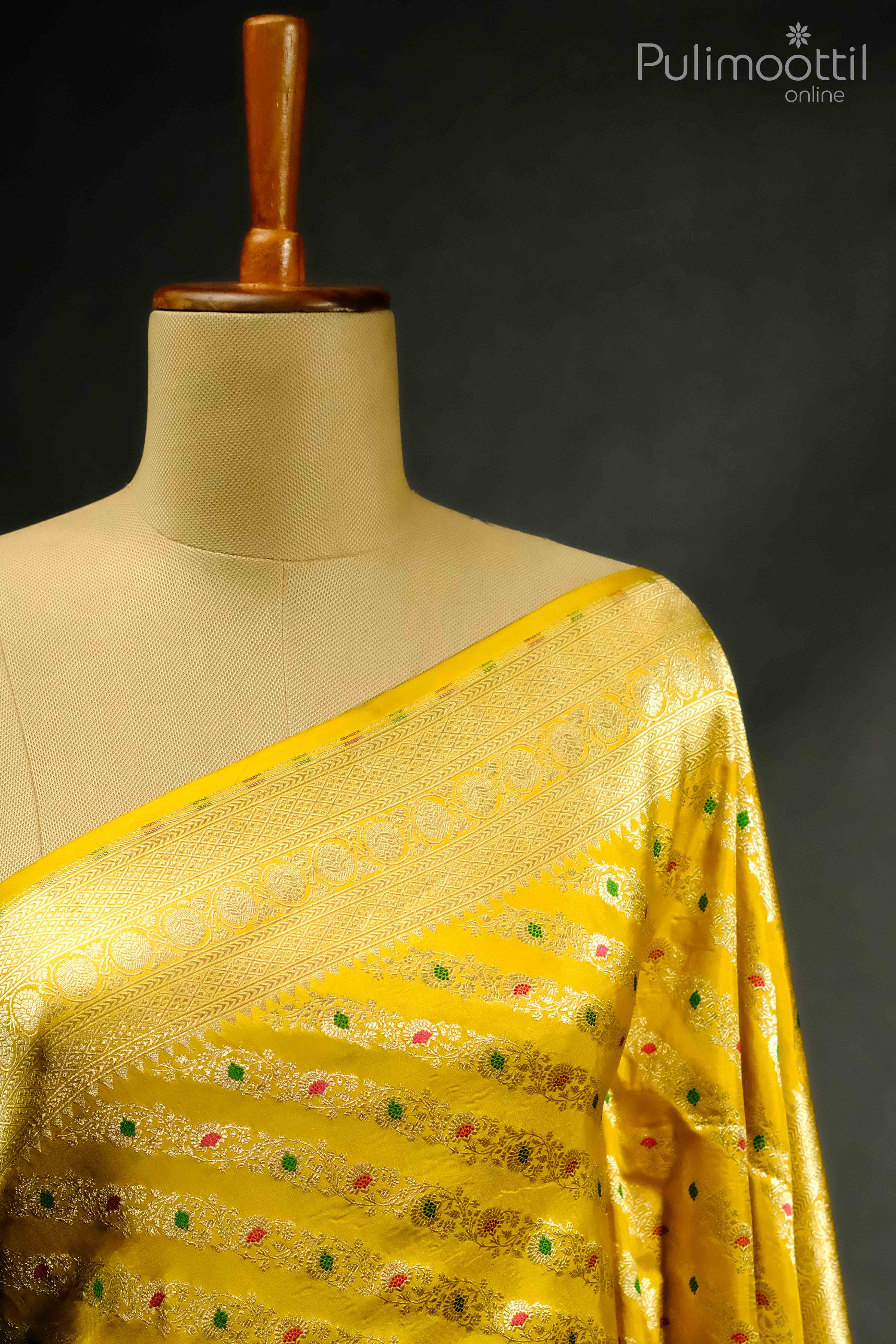 Close-up of lemon yellow pure Banarasi silk saree showcasing intricate floral design patterns in pink, green, and gold, with a rich golden border, perfect for weddings and festive events.