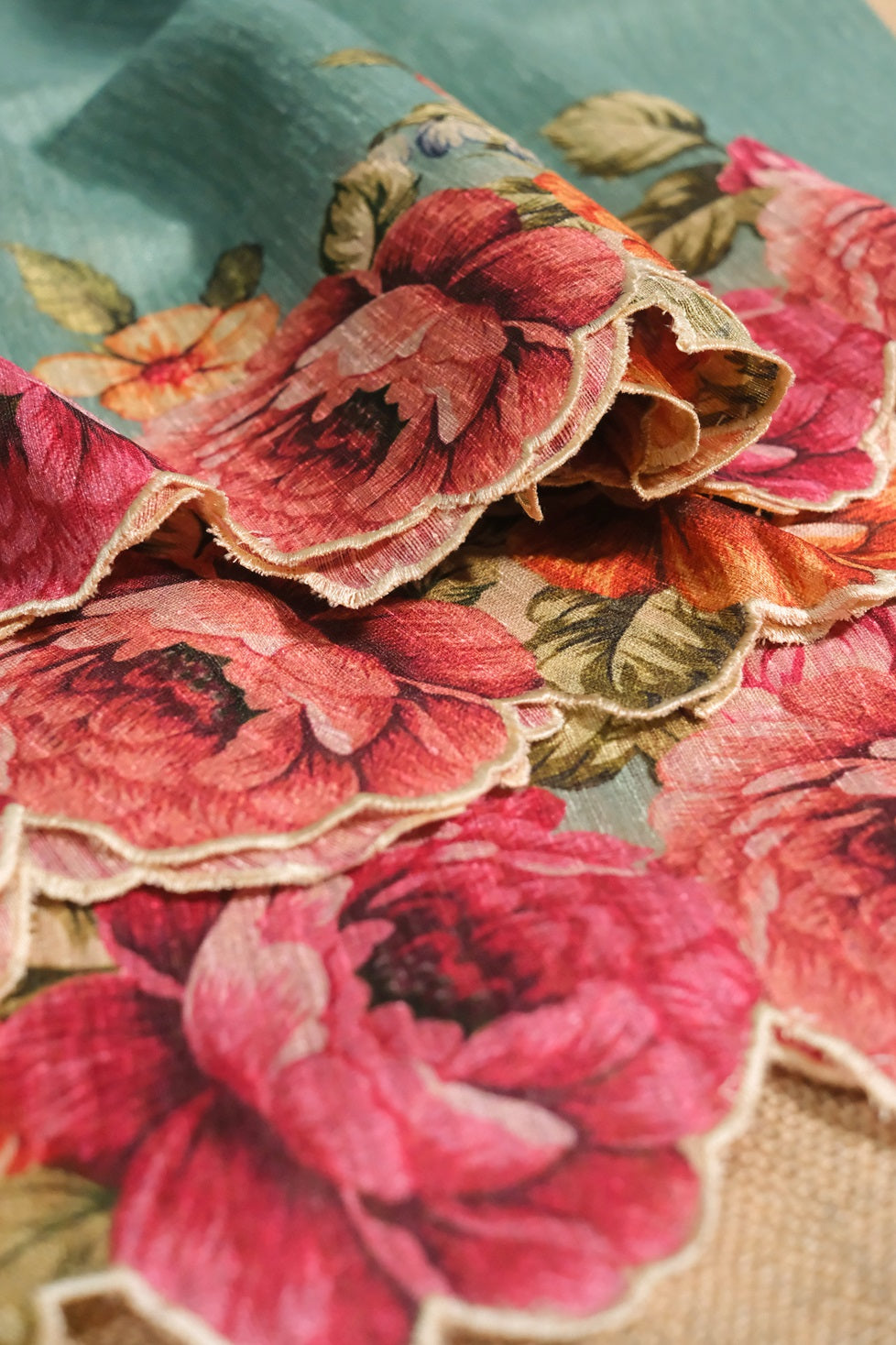 Floral patterned semi jute saree in light teal color showcasing vibrant rose prints and soft fabric texture.