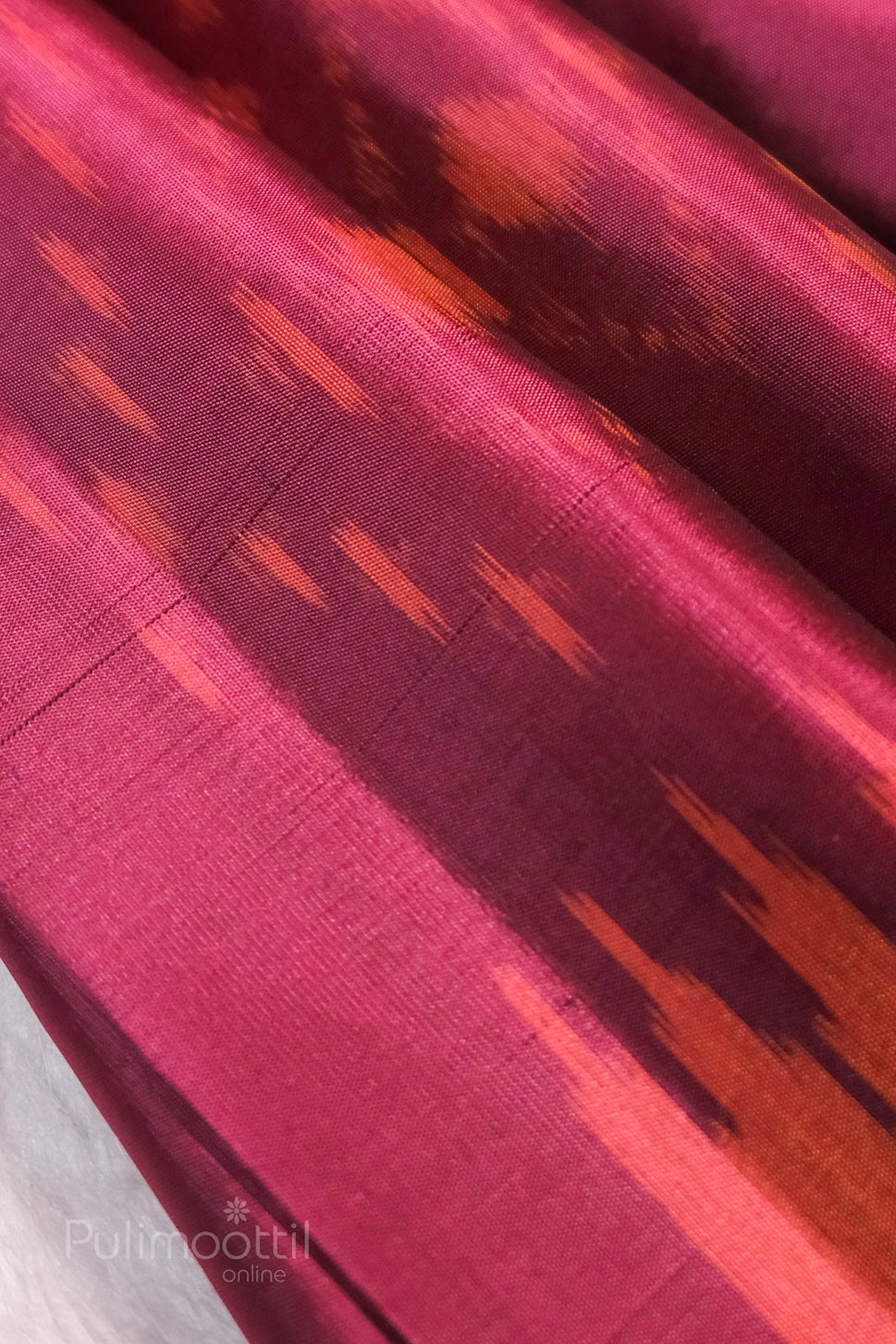 Magenta-pink Kanchipuram soft silk saree close-up, featuring orange-pink ikkat pattern on luxurious silk fabric