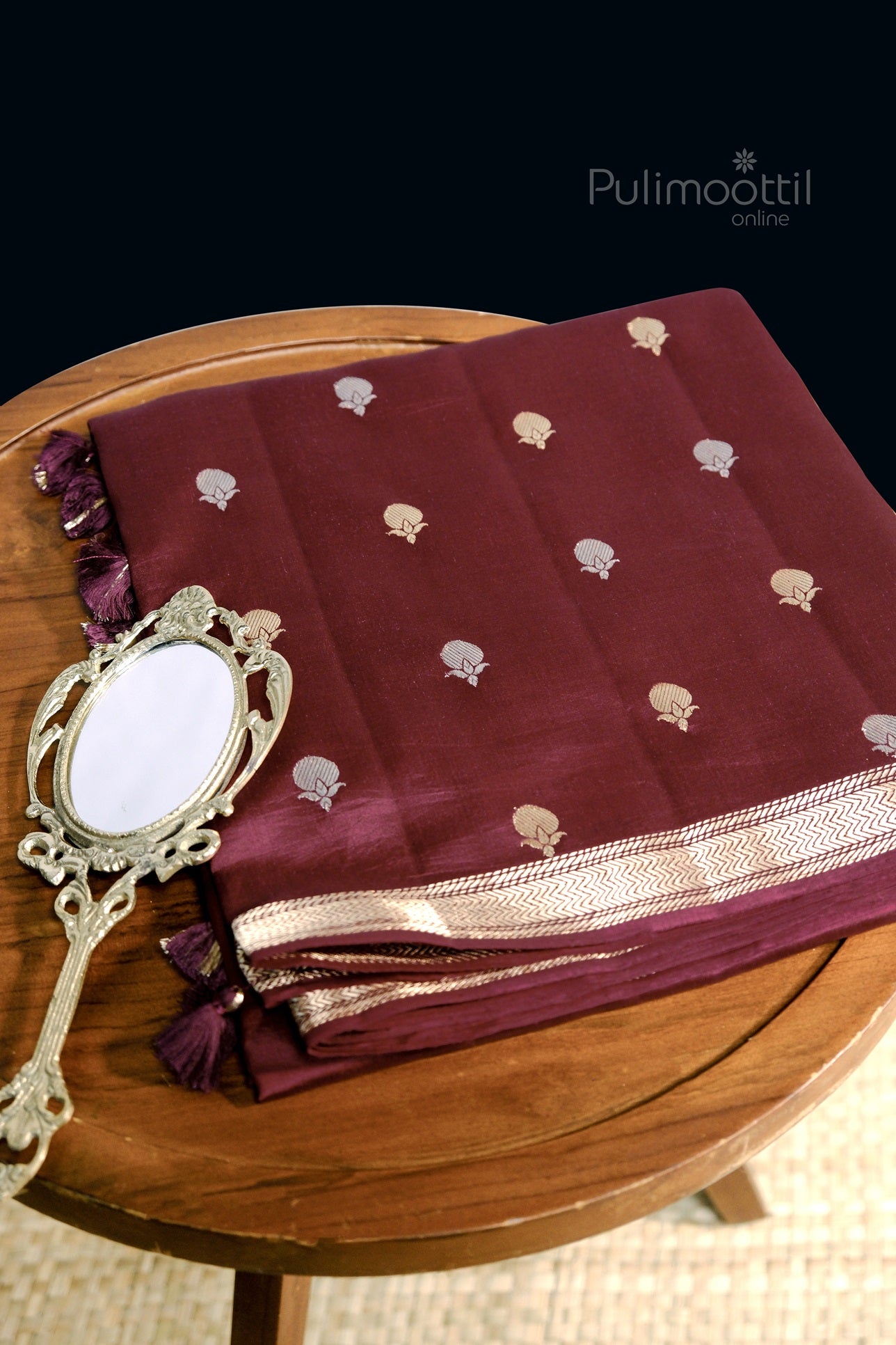 Cobalt blue pure mango silk saree neatly folded with golden zari motifs and border, placed on a wooden table with a vintage mirror.