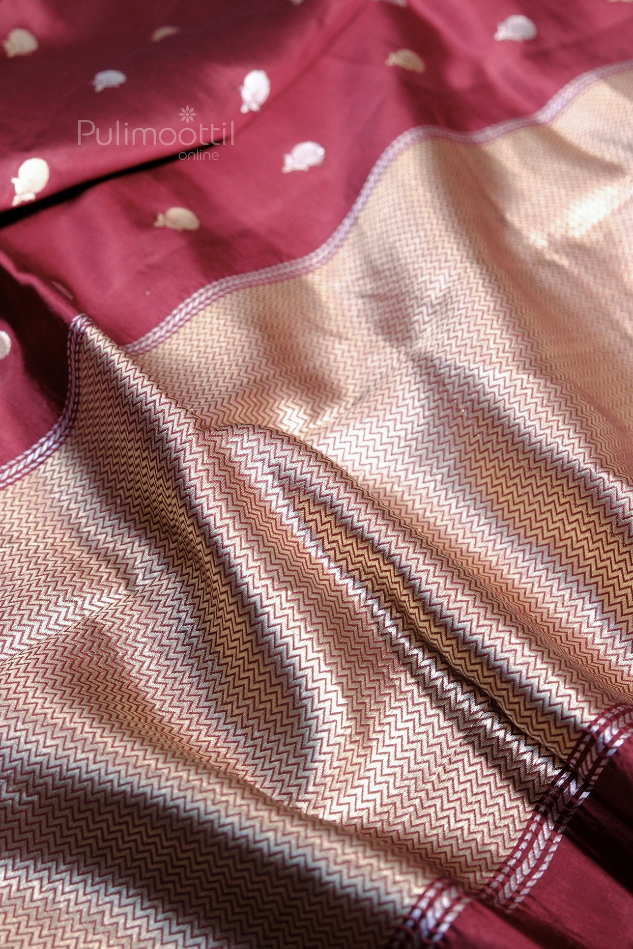 Close-up of the rich golden zari pallu with intricate chevron patterns on the cobalt blue mango silk saree.