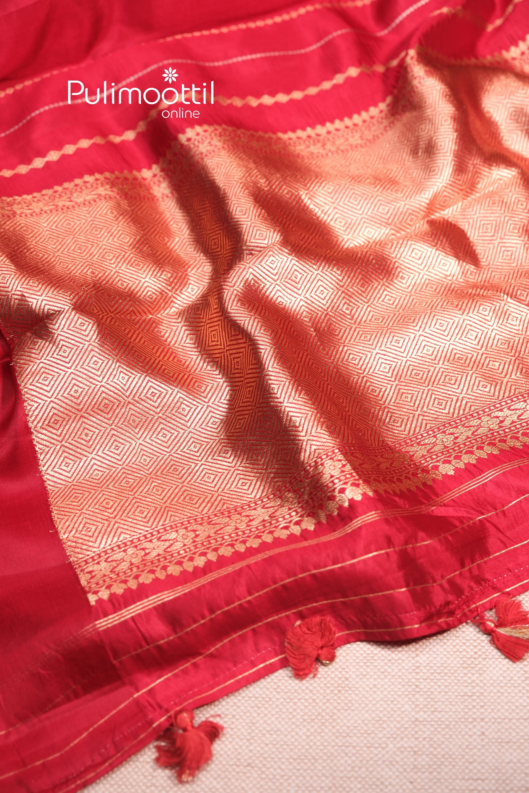 Close-up of the maroon mango silk saree pallu, showcasing intricate gold zari weaving in geometric diamond patterns, along with traditional border detailing.