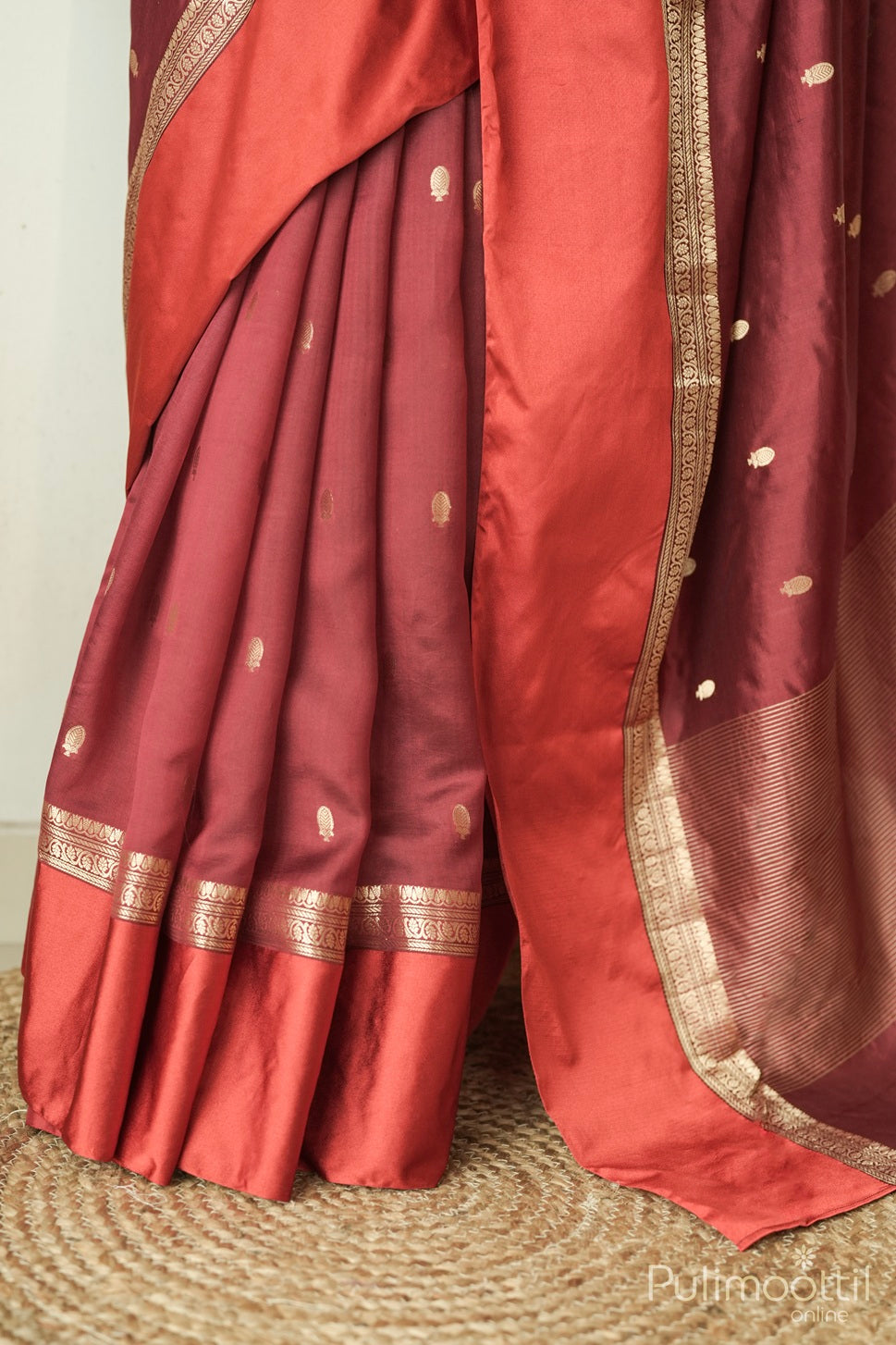 Detailed view of maroon silk saree showcasing golden motifs and ornate satin border craftsmanship.