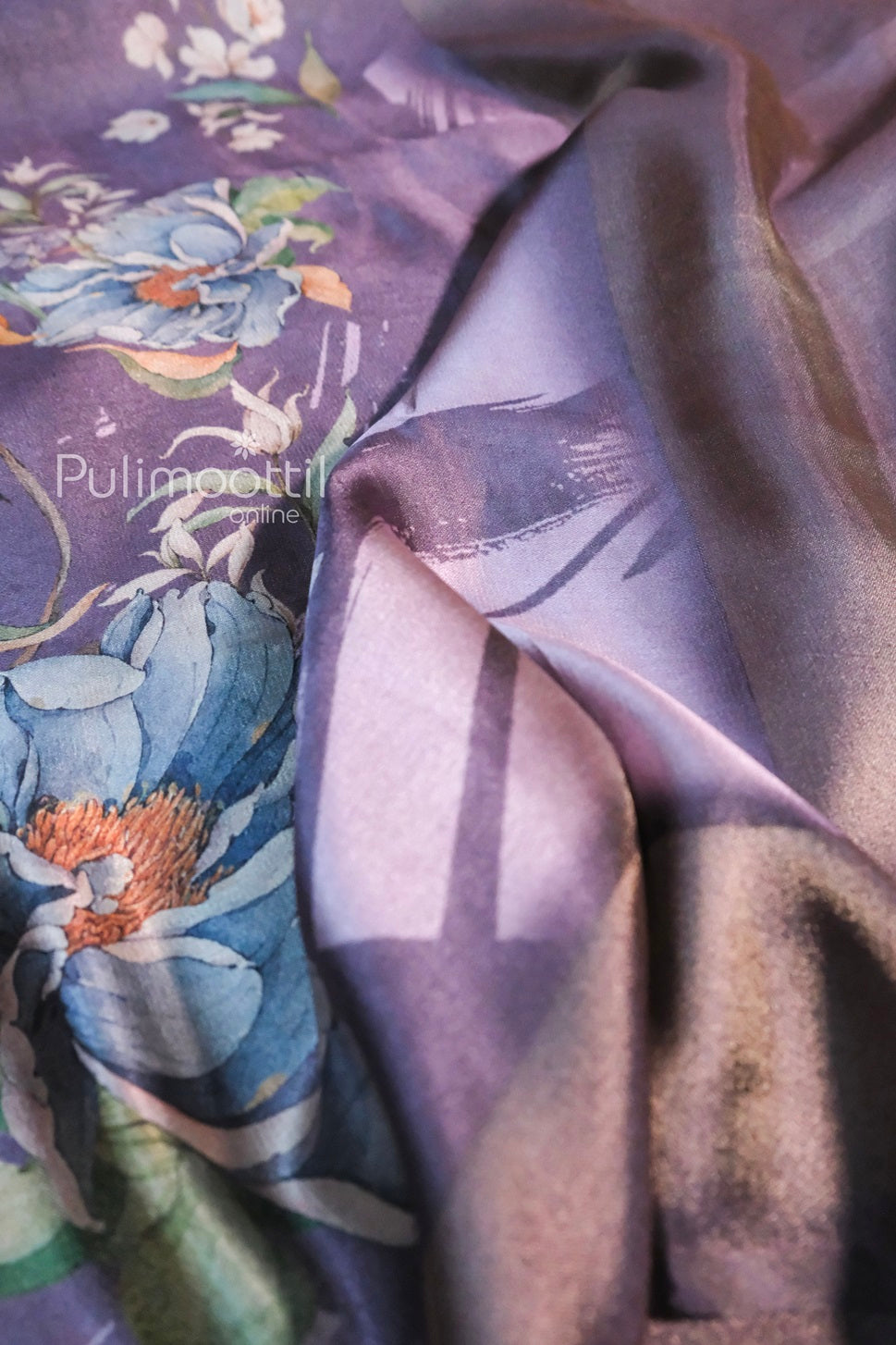 Close-up of lavender tissue silk saree featuring vibrant floral digital prints in blue, green, and orange hues, with a soft shimmer and elegant drape.