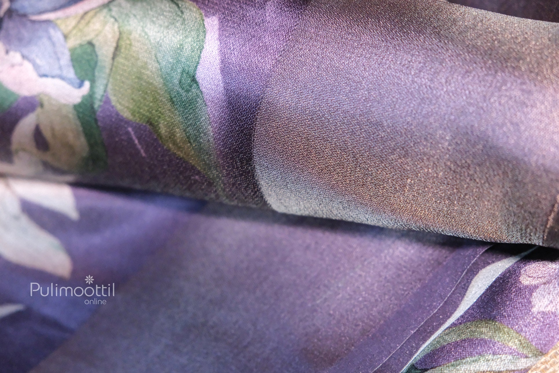 Lavender-colored tissue silk saree with soft floral print details in green and white tones, showcasing its smooth, glossy texture and elegant finish.