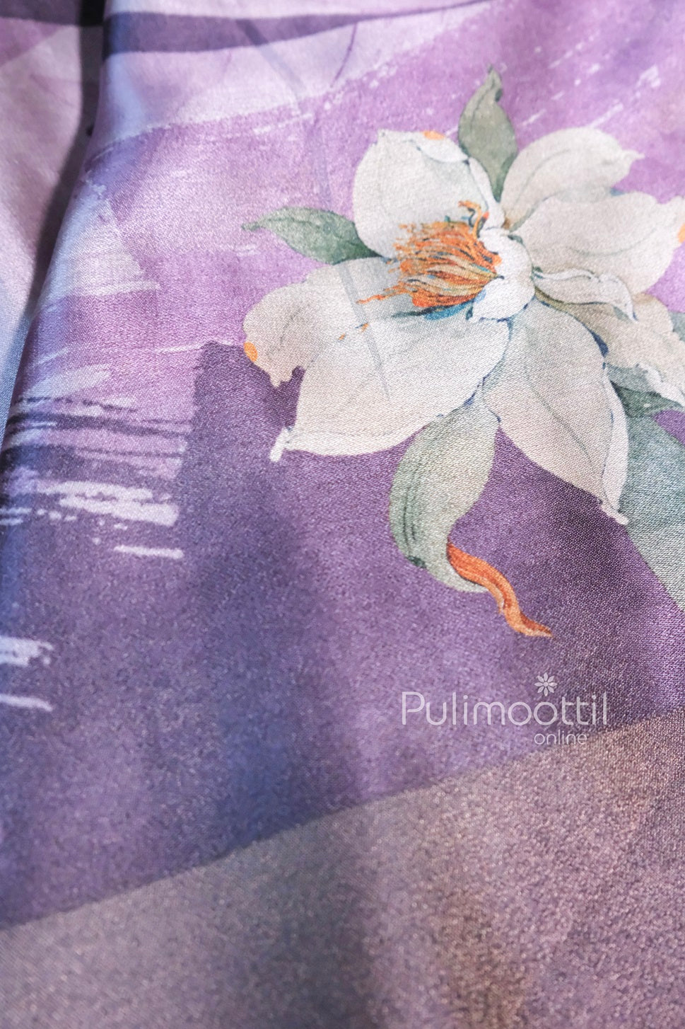 Lavender-colored tissue silk saree with soft floral print details in green and white tones, showcasing its smooth, glossy texture and elegant finish.