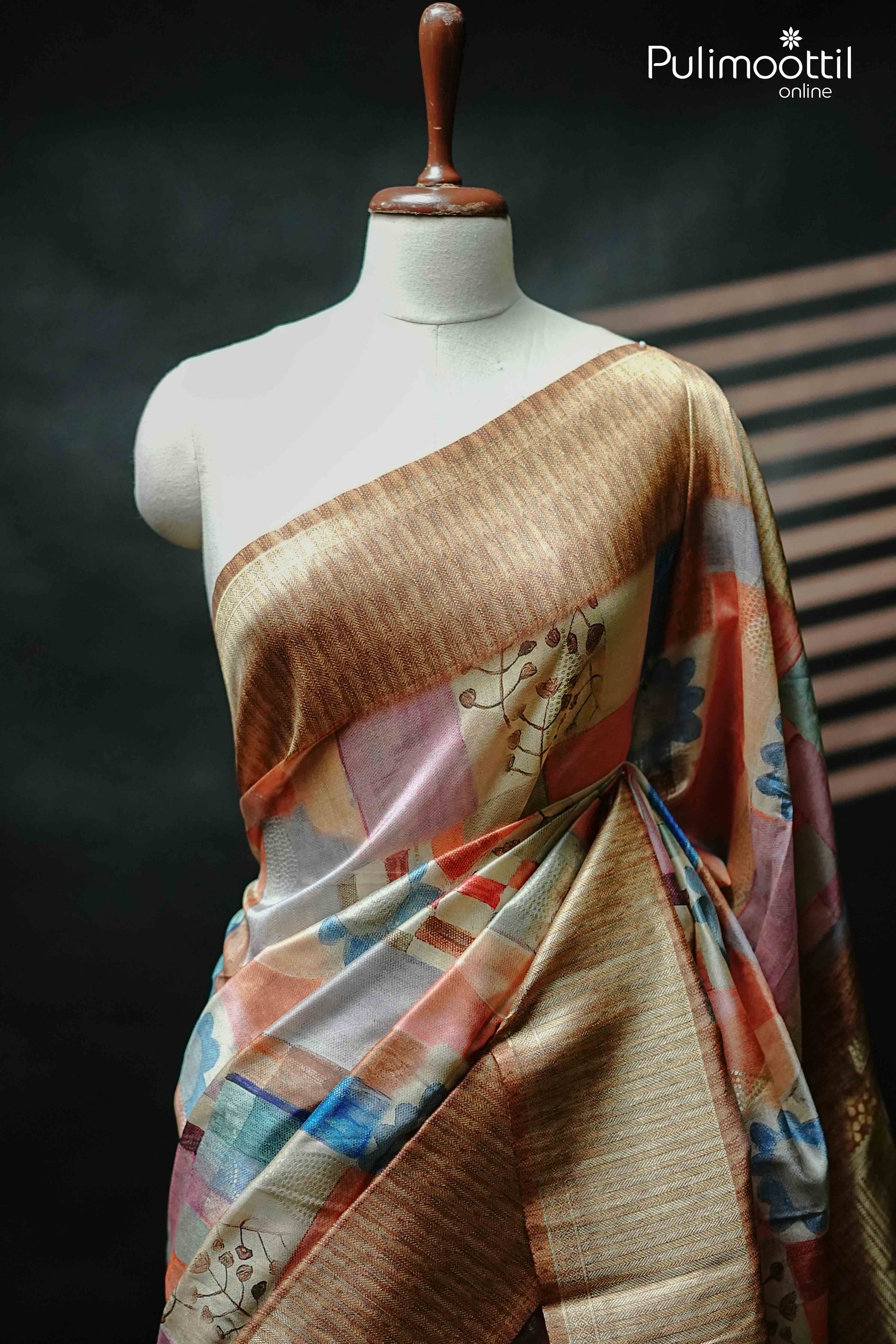 Multi colour semi jute saree draped on mannequin, featuring floral and geometric prints with a contrast golden border – ideal Onam Kerala saree for women.