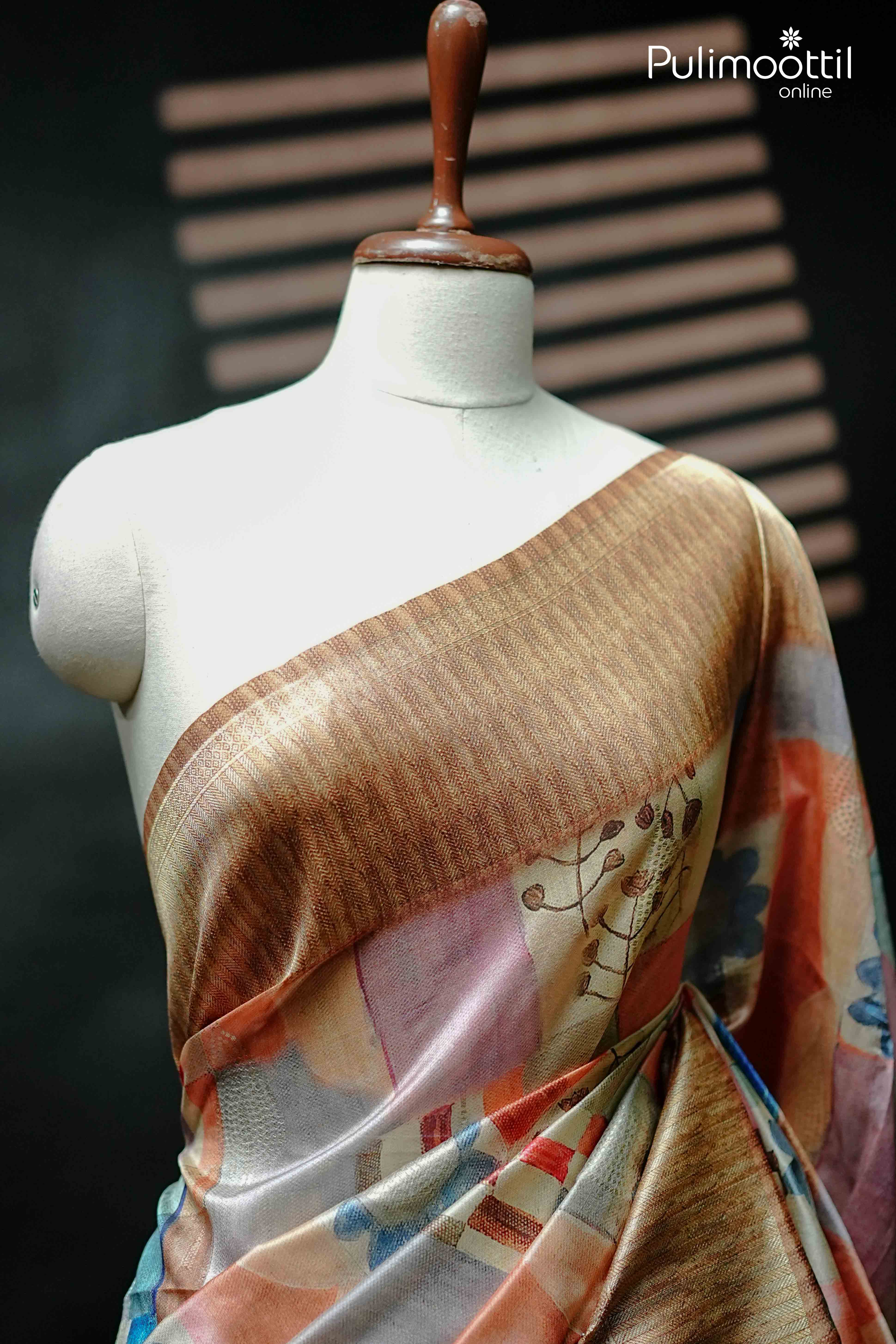 Front view of mannequin draped in multi colour semi jute saree with floral and abstract print, featuring rich golden brown woven border.