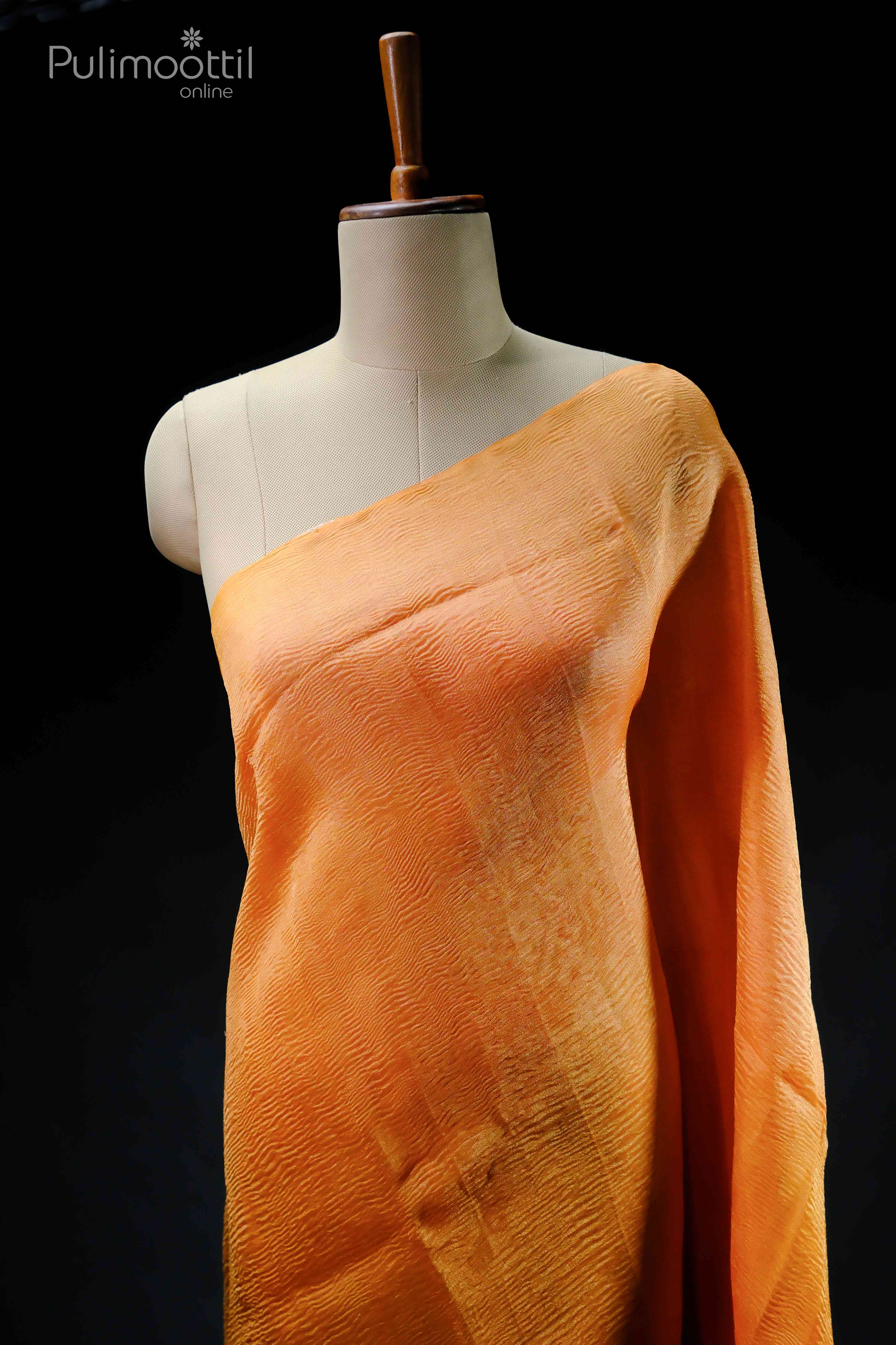 Neon orange crushed tissue saree draped on a mannequin, plain without border.