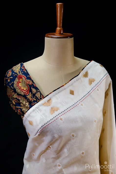 Off white Chanderi silk saree with golden zari butta motifs and red-black running stitch border, paired with a contrasting navy blue floral embroidered blouse – displayed on mannequin against black background.