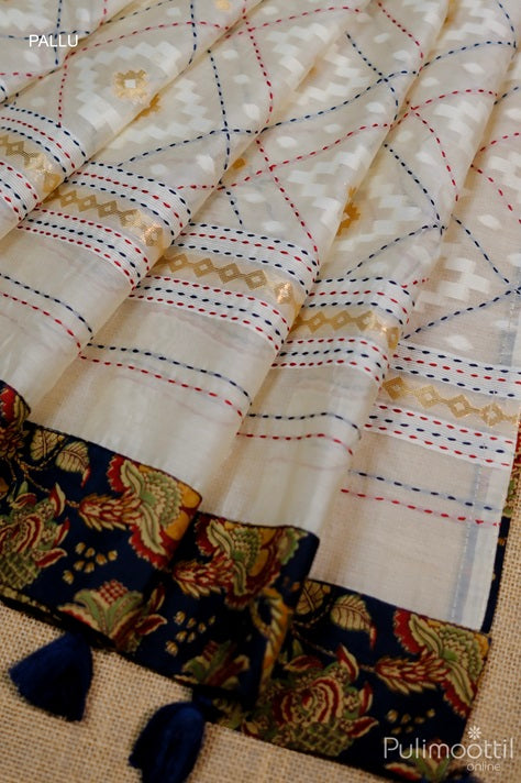 Pallu of off white Chanderi silk saree featuring multicolour running stitch lines, golden zari motifs, and a navy blue floral woven border with tassel accents – elegant finish for festive and bridal wear.