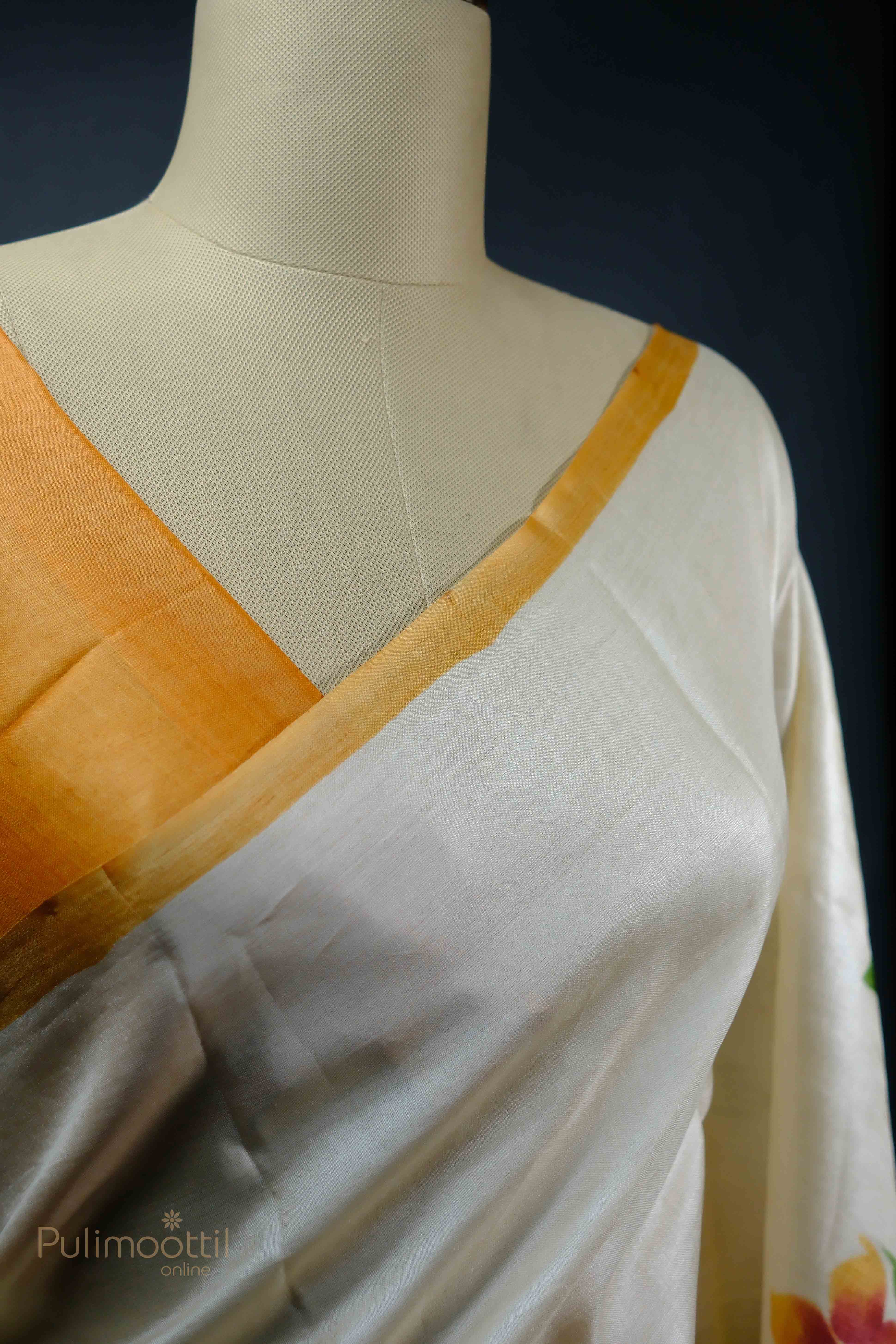 Off-white Tassar saree with floral design and orange border, draped on a mannequin showcasing the blouse and pallu.