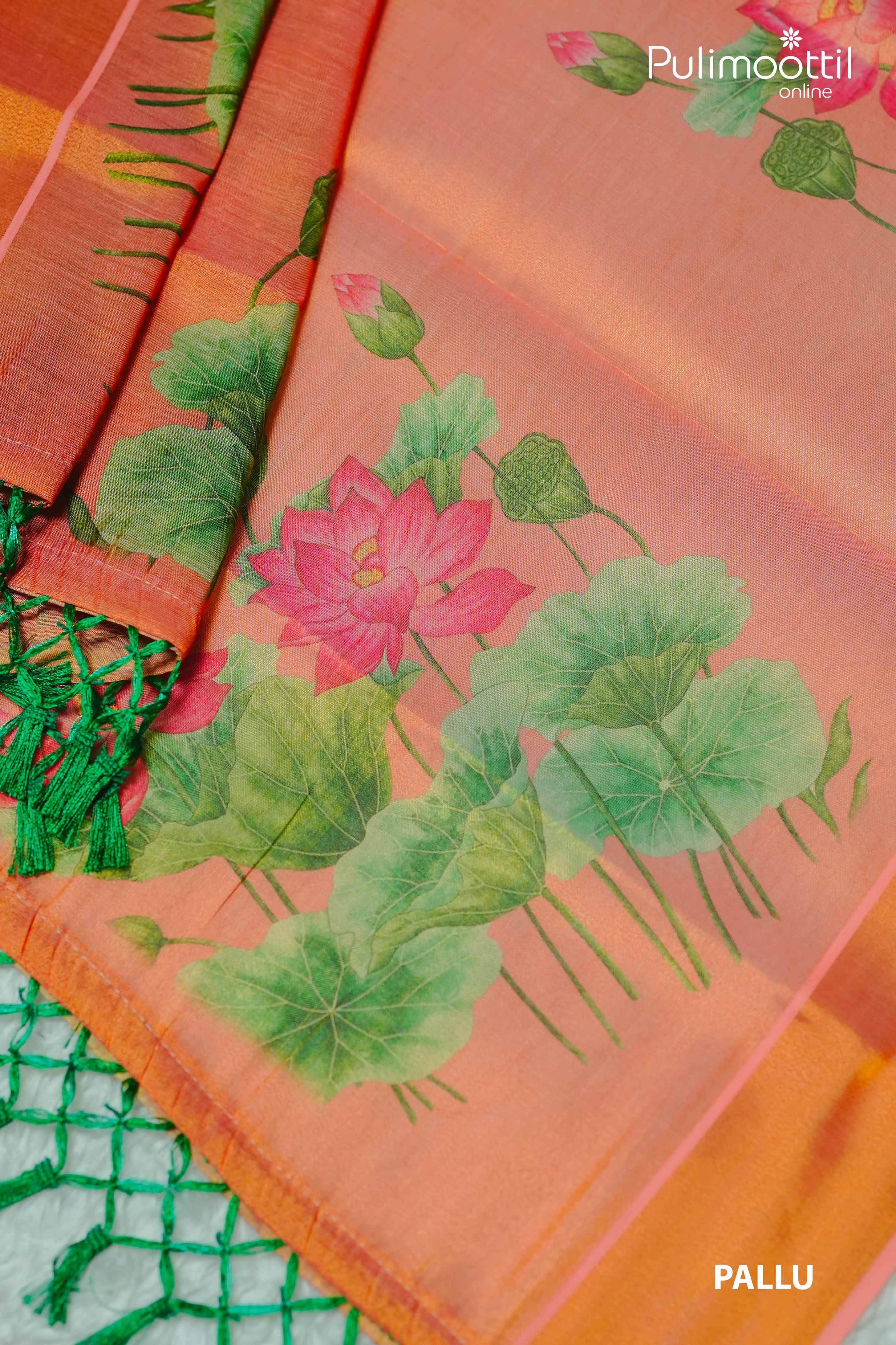 Close-up of orange Kerala tissue set saree pallu featuring vibrant lotus flower print, green lotus leaves, and green tassels on the border.