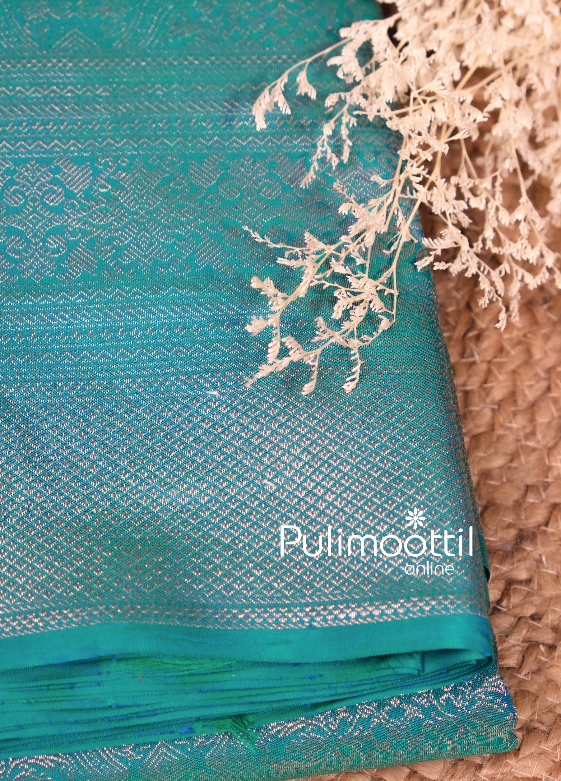 Folded peacock green Kanchipuram silk saree with silver zari border, ideal for brides seeking a traditional, luxurious look for weddings or festivals.