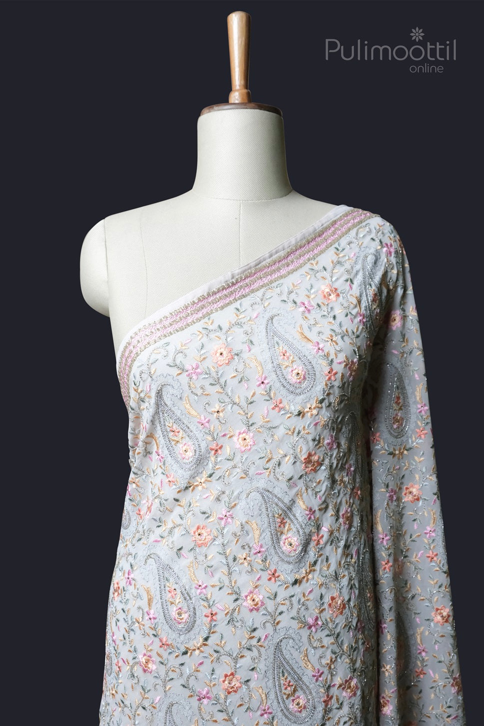 Light grey net saree with pastel floral embroidery and paisley motifs, displayed on a mannequin with embellished border