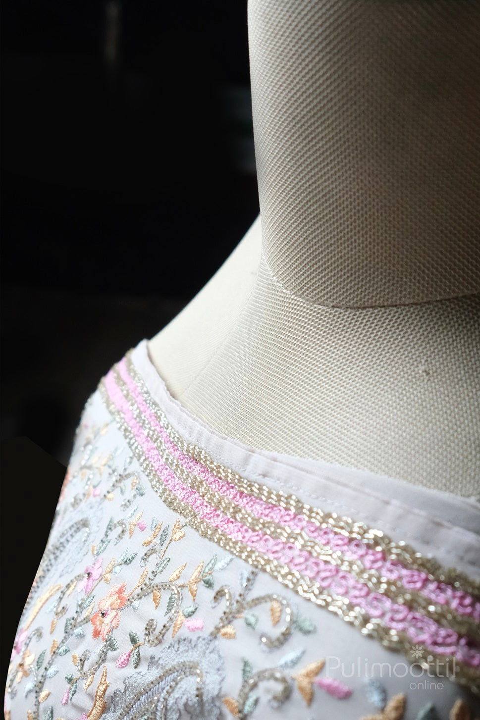 Zoomed-in view of pink and gold embroidered border on light grey net saree with floral and paisley threadwork