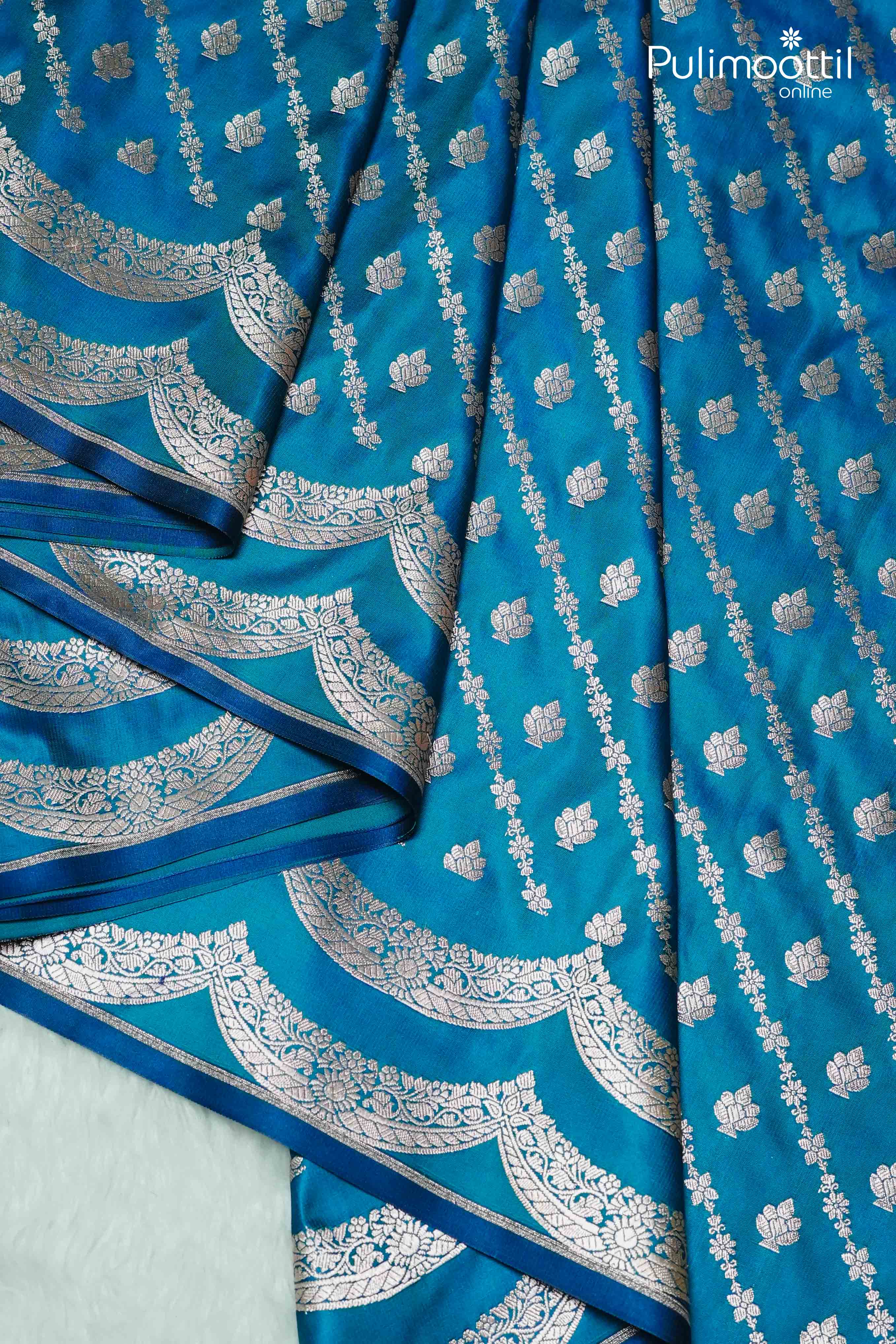 "Peacock blue Banarasi silk saree with silver zari floral buttas and elegant scalloped border – Pulimoottil Online
