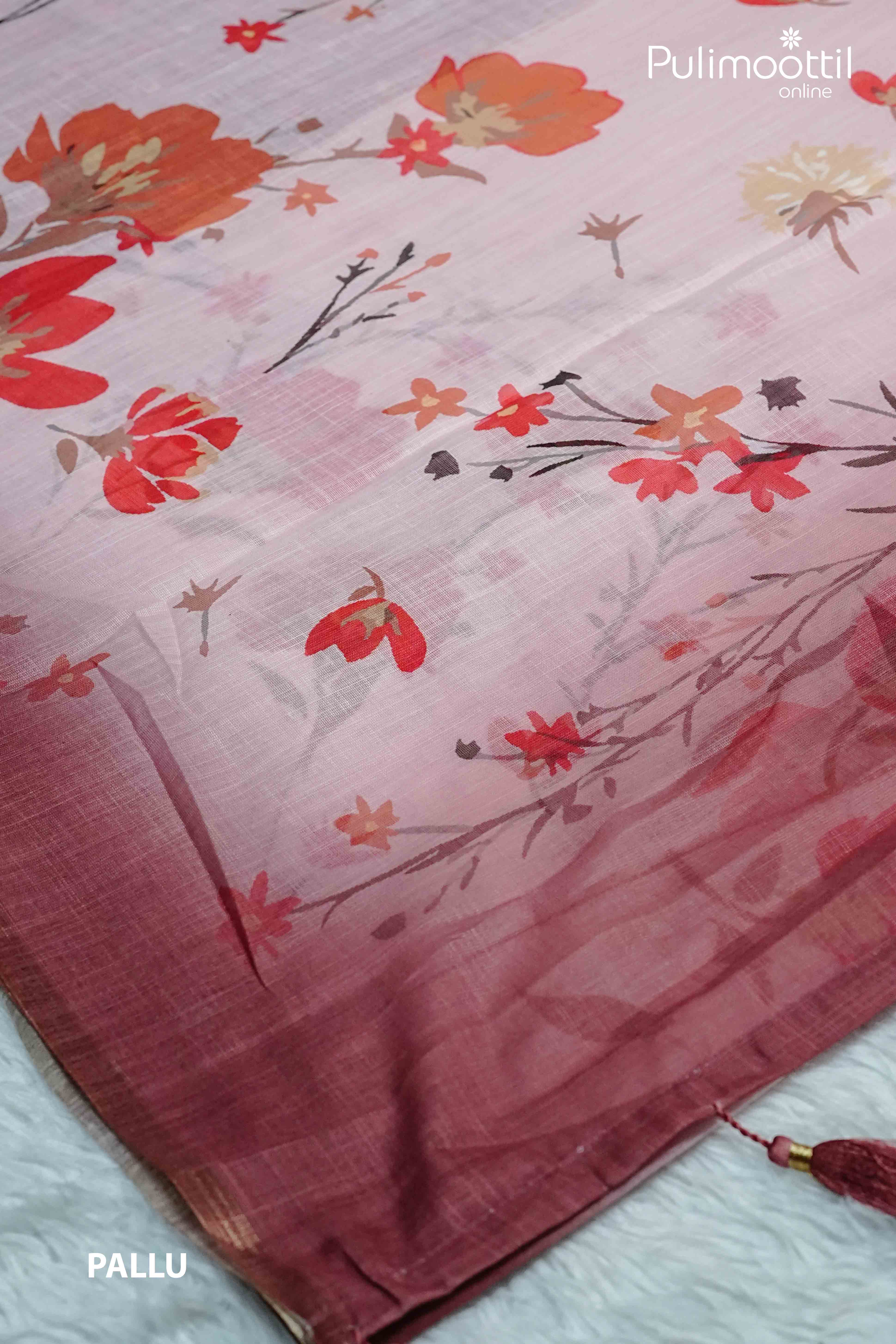 Pallu of pink semi linen saree with red and orange floral prints, soft gradient texture, and small contrast tissue border with tassel finish.