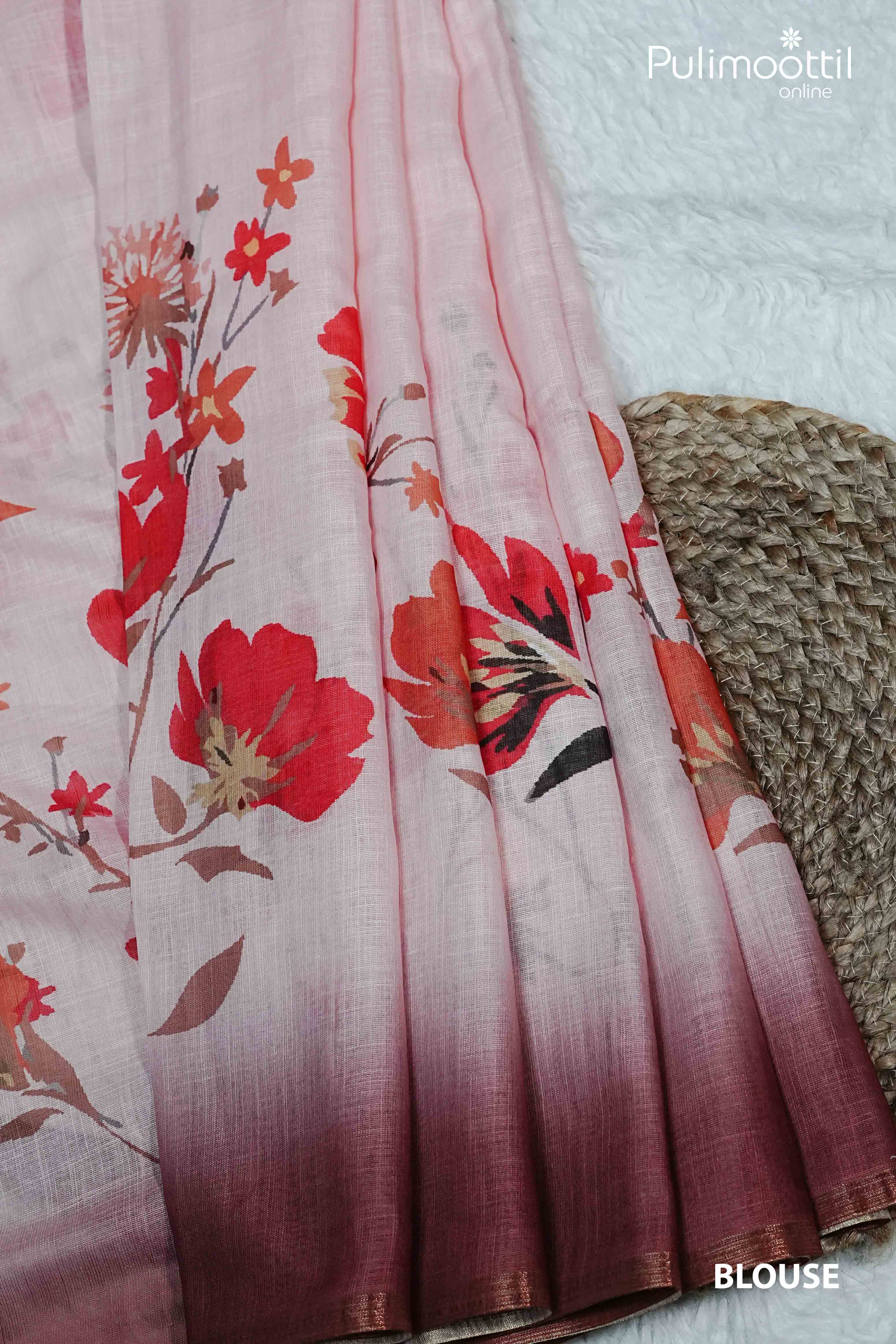 Pleated pink semi linen saree with bold red floral prints, soft gradient transition to maroon, and delicate contrast tissue border on display.
